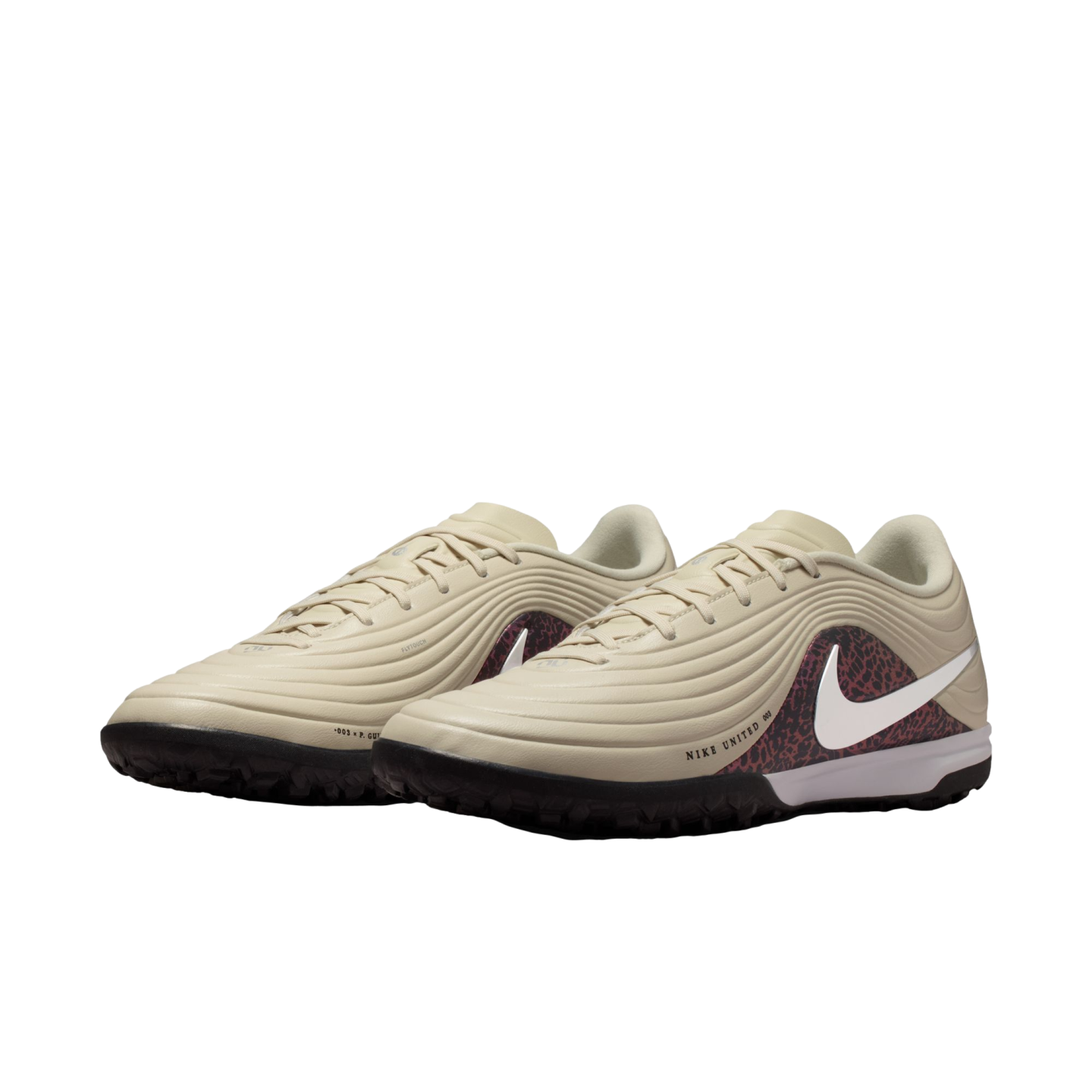 A pair of cream-colored Nike soccer turf shoes with a reddish-pink leopard print pattern on the sides, featuring a white swoosh logo and black outsoles.