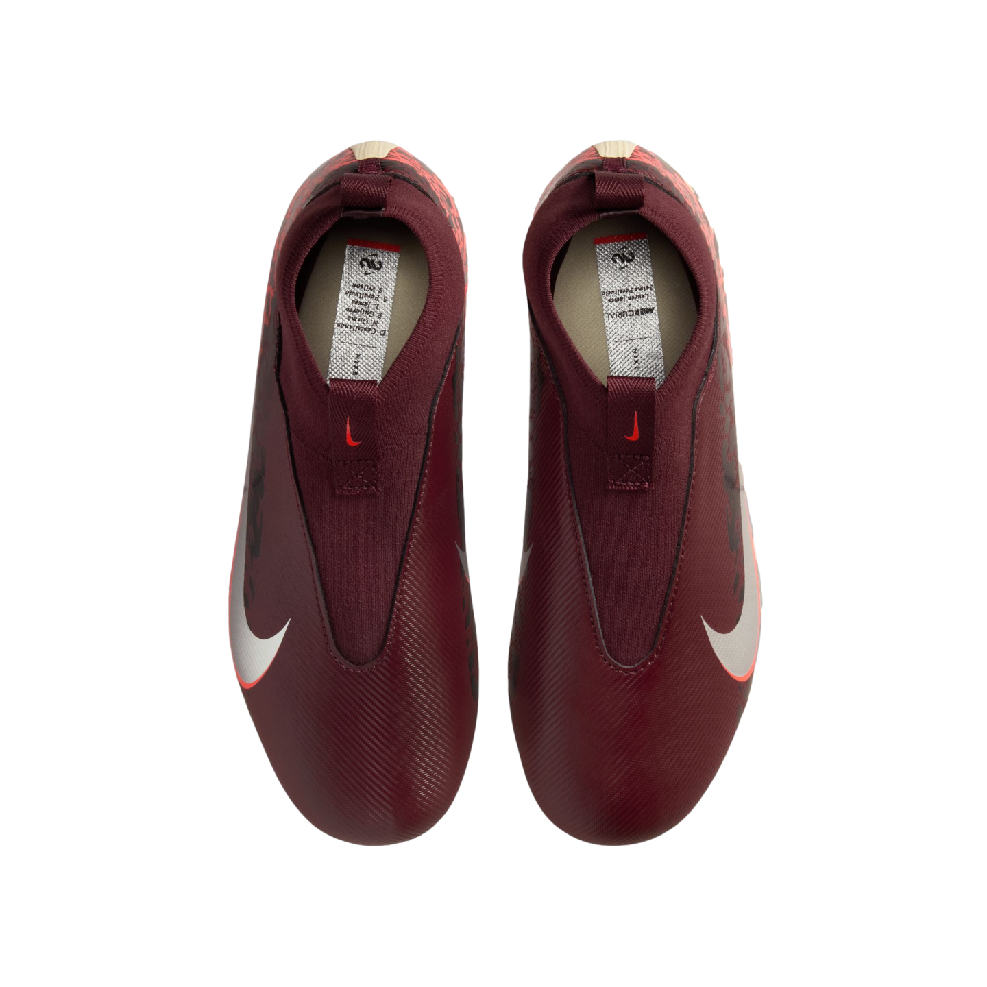 A top-down view of a pair of laceless, maroon Nike soccer cleats against a solid black background. The shoes feature large white Nike swooshes on the sides and a textured upper.