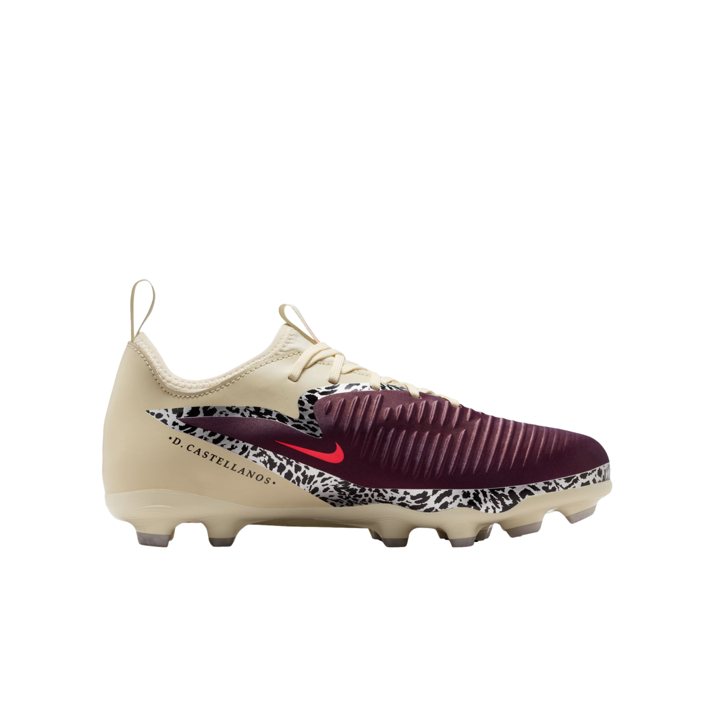 A profile view of a Nike soccer cleat against a solid black background. The shoe features a cream-colored upper, a maroon ribbed toe, and a black-and-white speckled pattern across the mid-section with a small red Nike swoosh. The name ".D. CASTELLANOS." i