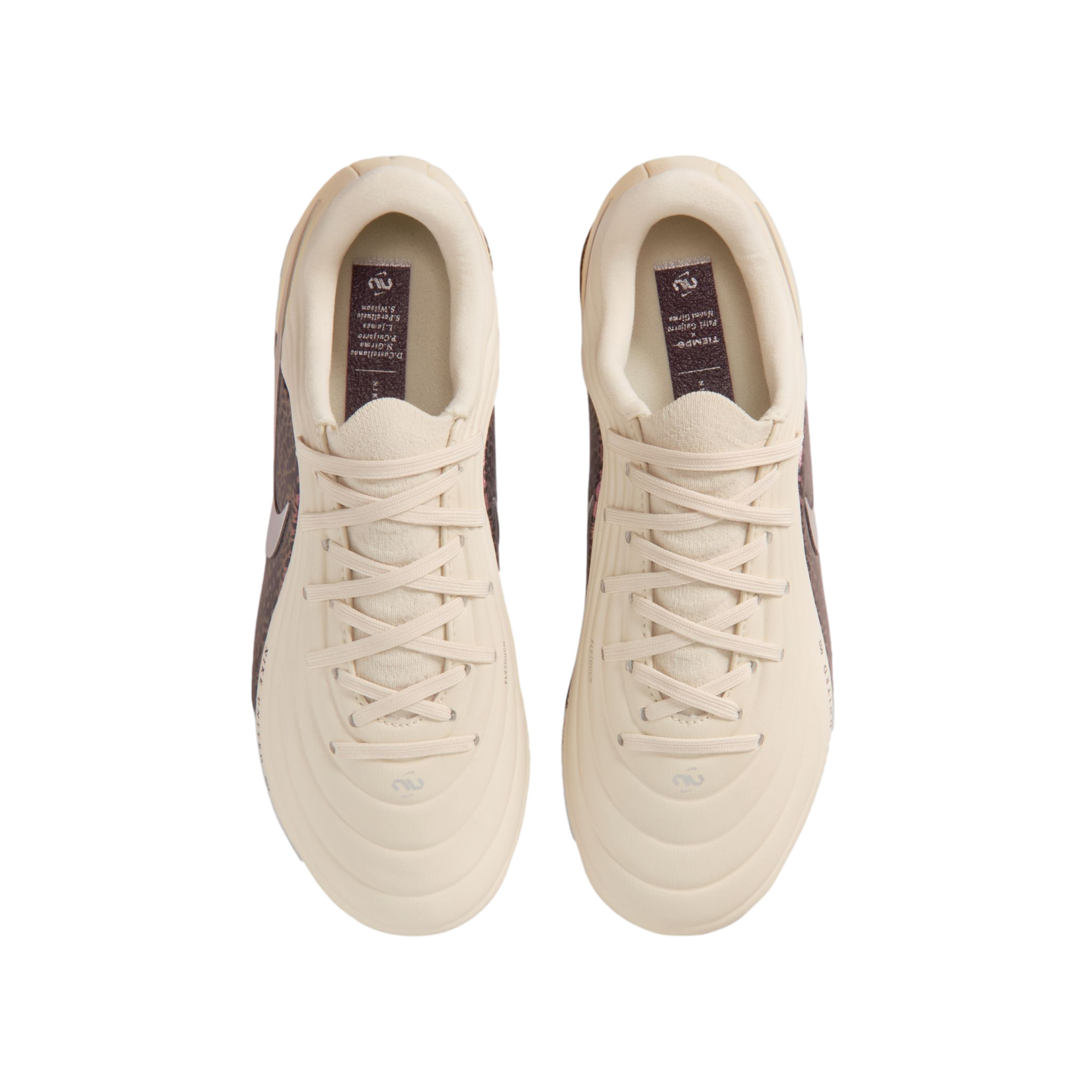 A top-down view of a pair of cream-colored Nike Tiempo soccer cleats centered against a black background. The shoes feature matching cream laces and a quilted, textured upper. Inside each shoe, a dark purple insole displays the "Tiempo" name and a list of