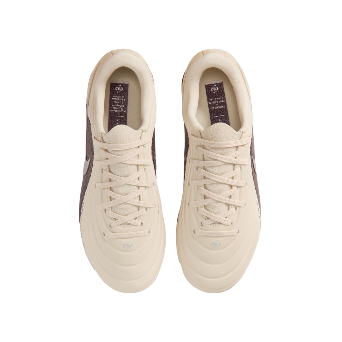 A top-down view of a pair of cream-colored Nike Tiempo soccer cleats centered against a black background. The shoes feature matching cream laces and a quilted, textured upper. Inside each shoe, a dark purple insole displays the "Tiempo" name and a list of