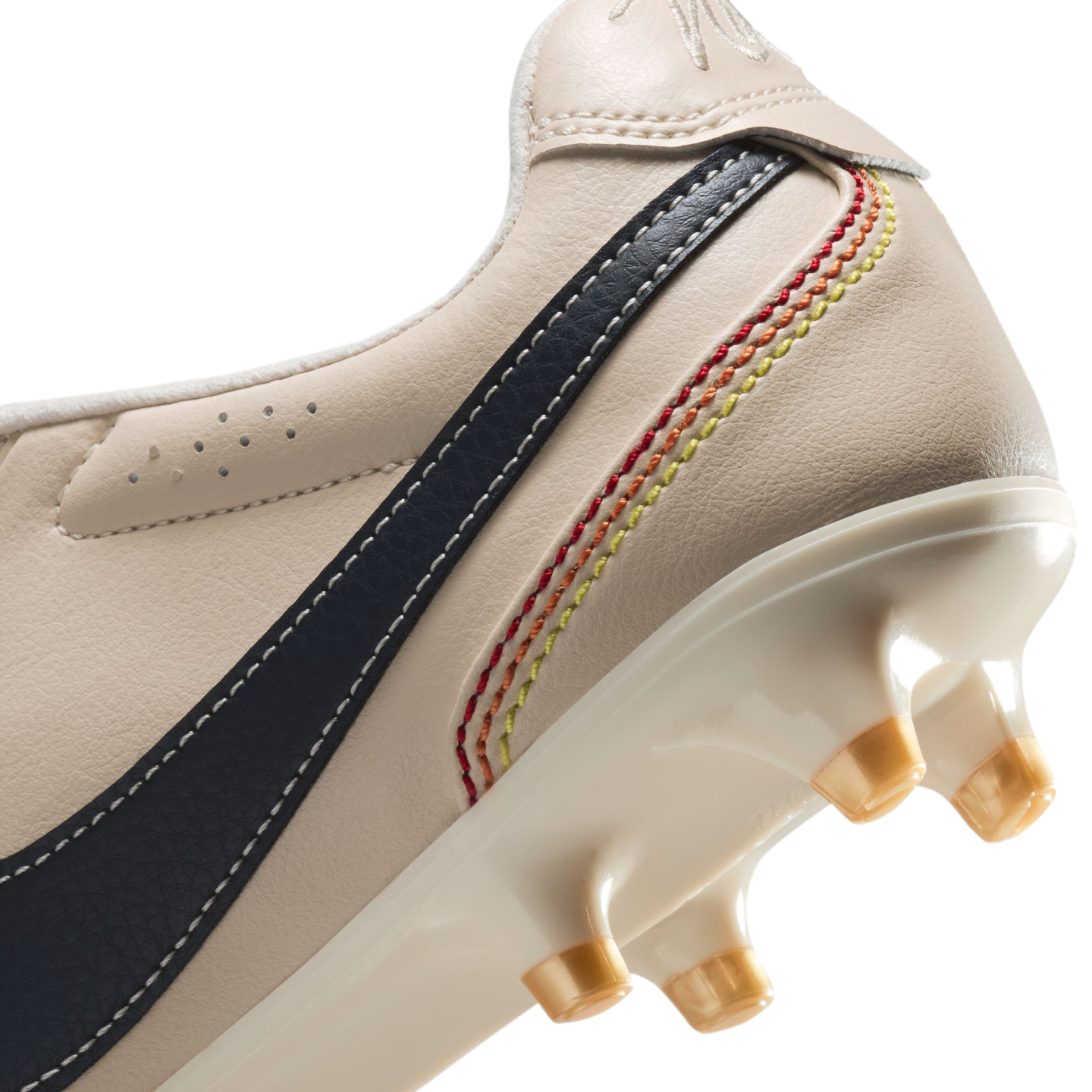 A close-up view of the heel and sole of an off-white leather soccer cleat. The shoe features a dark blue stripe with white stitching and five decorative, curved rows of stitching in a red, orange, and yellow gradient. The glossy white sole plate has trans