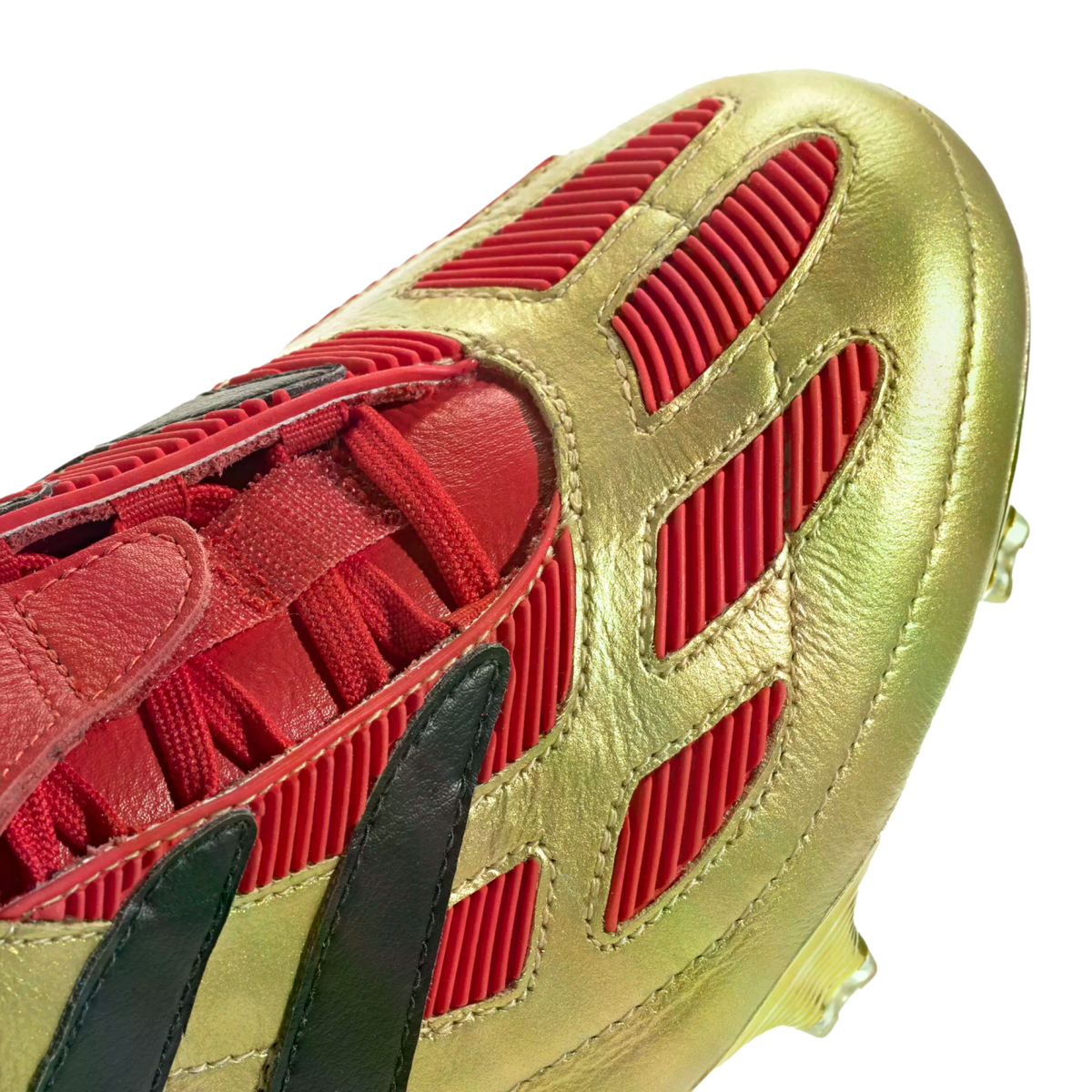 Close-up of a metallic gold soccer cleat featuring red ribbed rubber details, red laces, and black stripes.