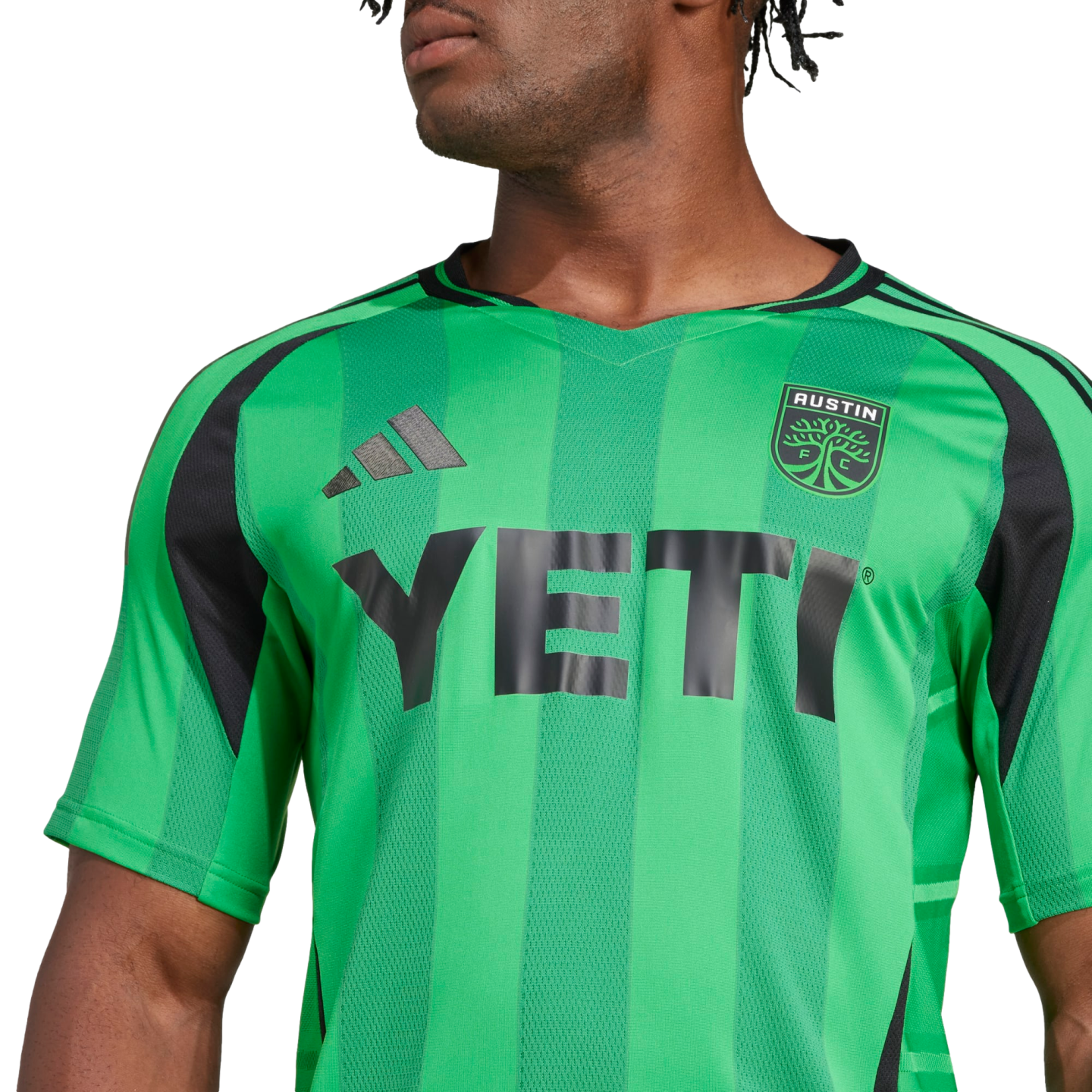 A person wearing a green and black striped Austin FC soccer jersey with the "YETI" logo on the front.