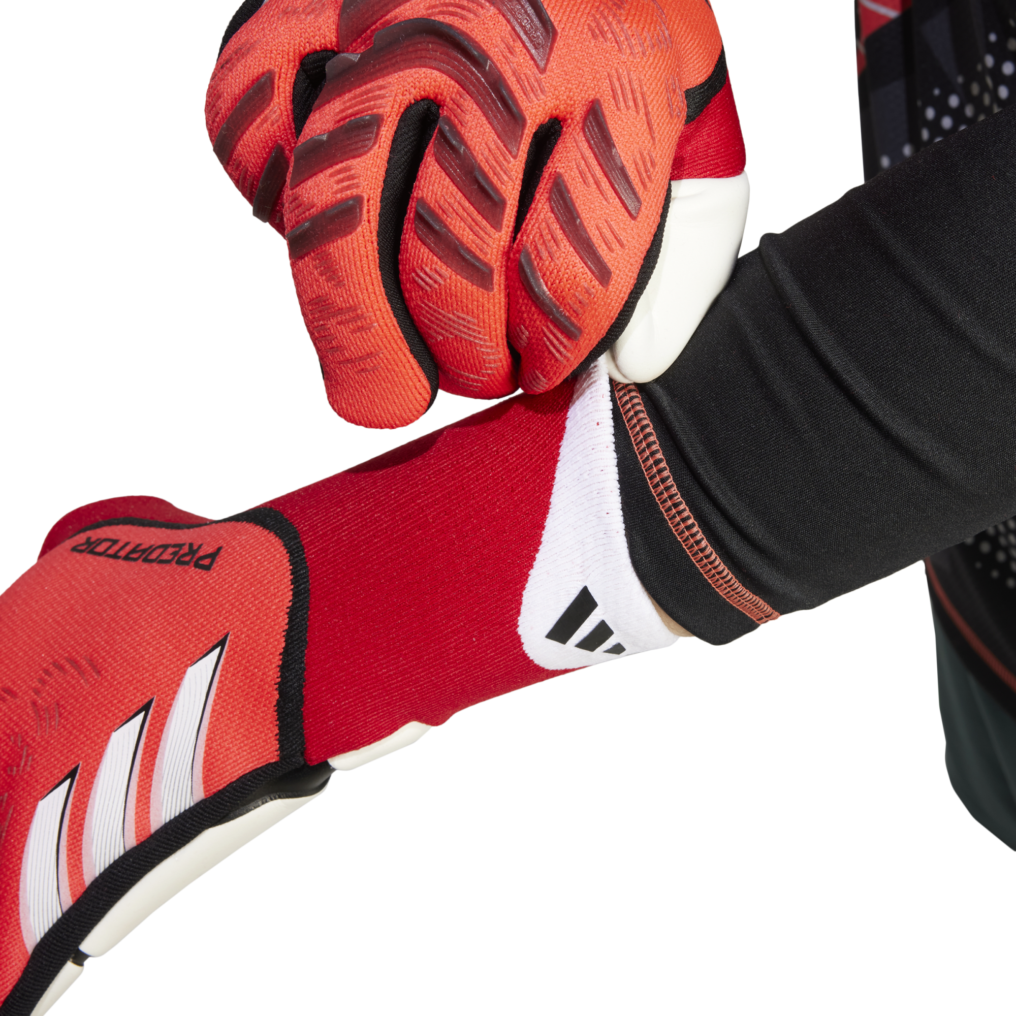 Close-up of a person putting on red Adidas Predator goalkeeper gloves, showing the textured grip and white brand logo.