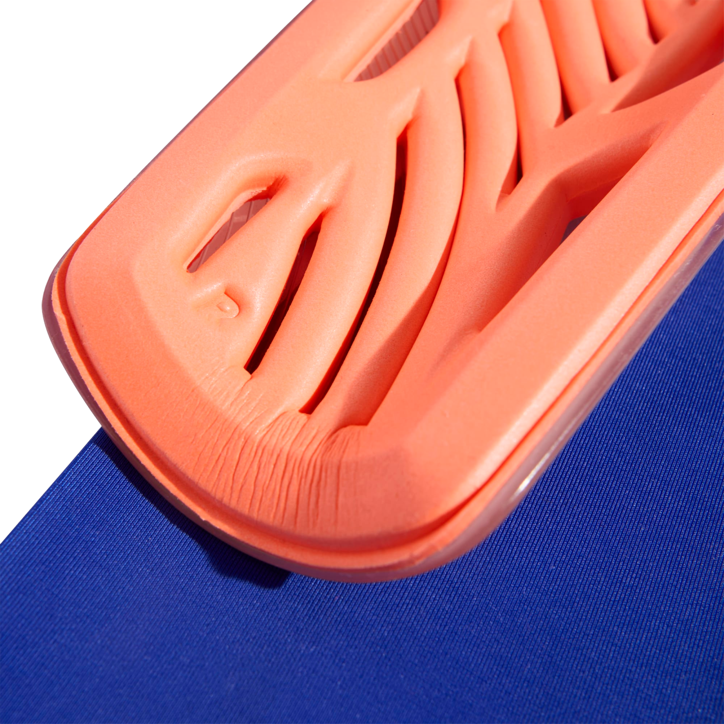 Close-up of a bright orange, ribbed foam padding resting on a blue textured surface.