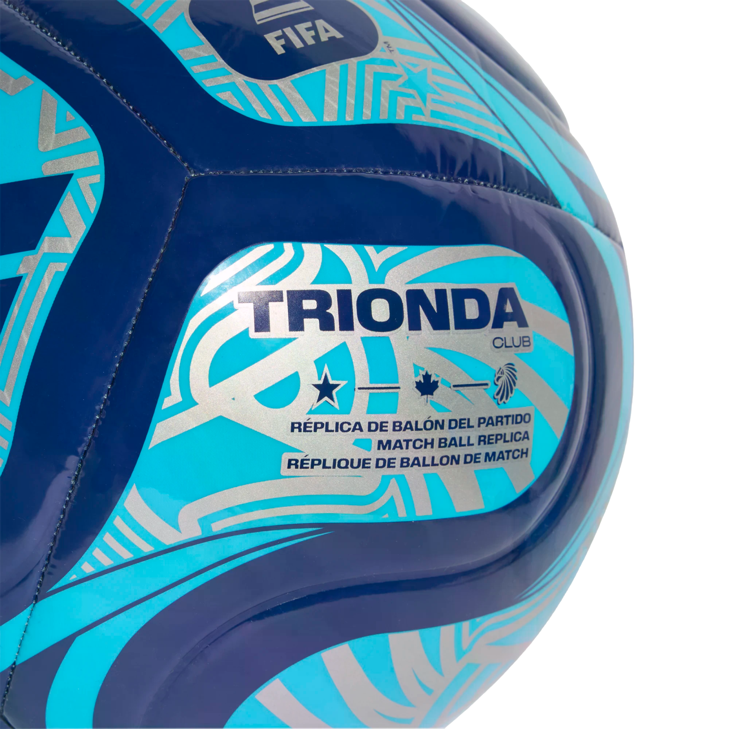 Close-up of a blue and turquoise soccer ball with silver patterns. Text reads "TRIONDA CLUB" and "MATCH BALL REPLICA" alongside FIFA, star, maple leaf, and lion head logos.