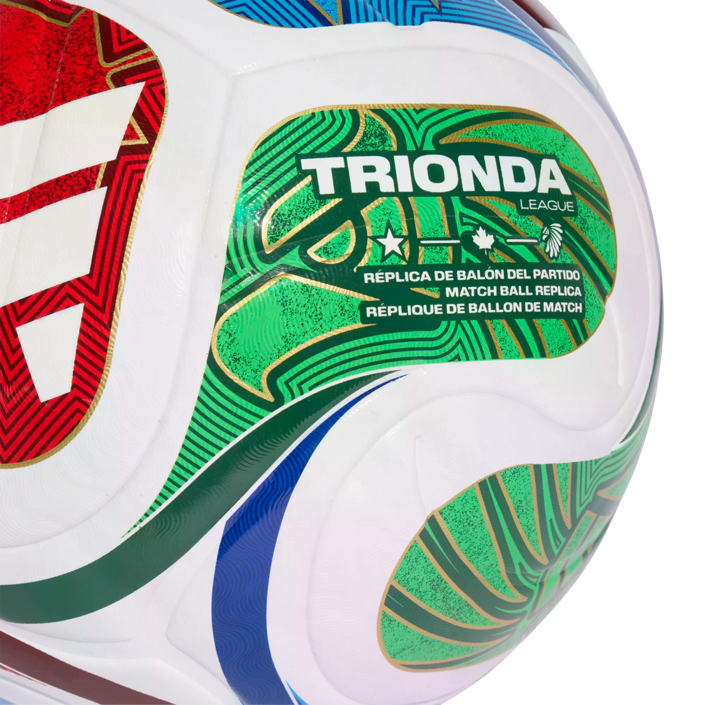 Close-up of a Trionda League replica soccer ball with green, gold, and red graphics. The ball features multilingual text and icons including a star, maple leaf, and eagle head.