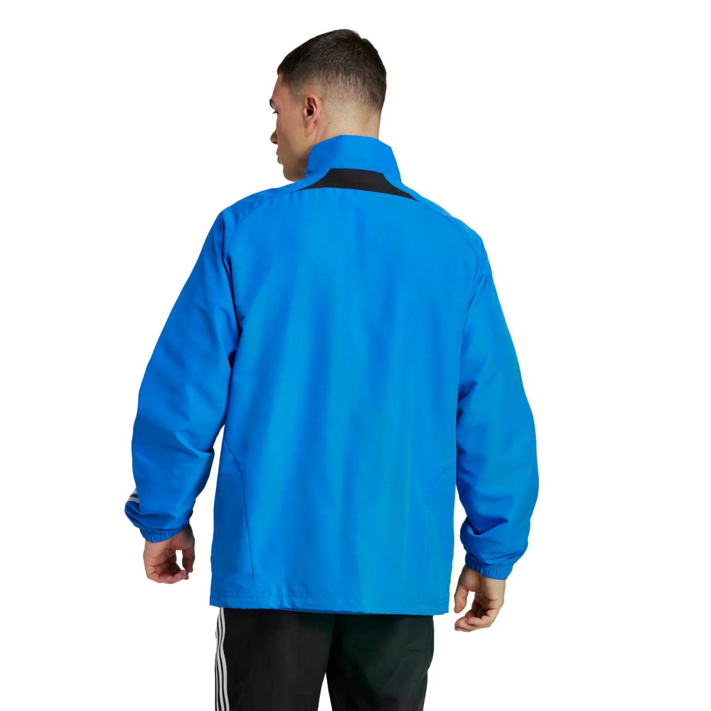 Rear view of a man wearing a bright blue athletic jacket and black striped track pants against a white background.