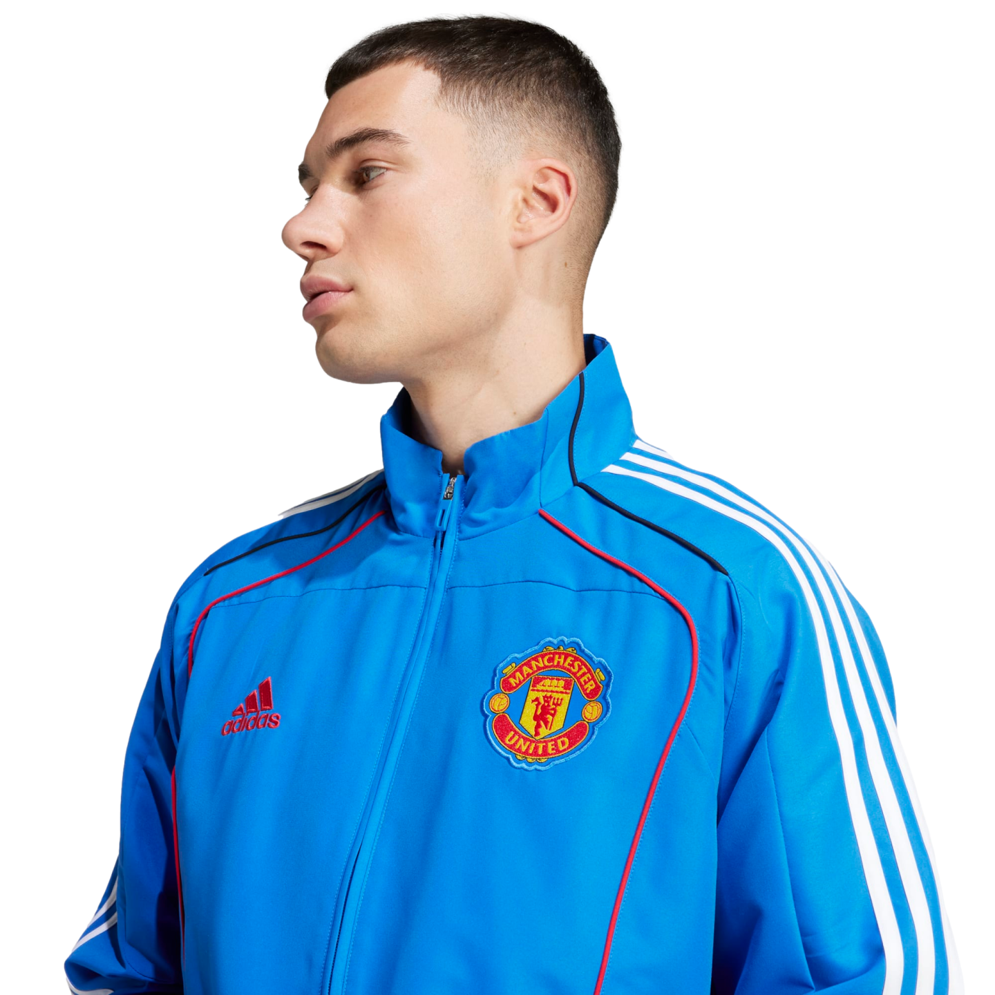 A man wearing a blue Manchester United track jacket with white stripes and a team crest, set against a plain white background.