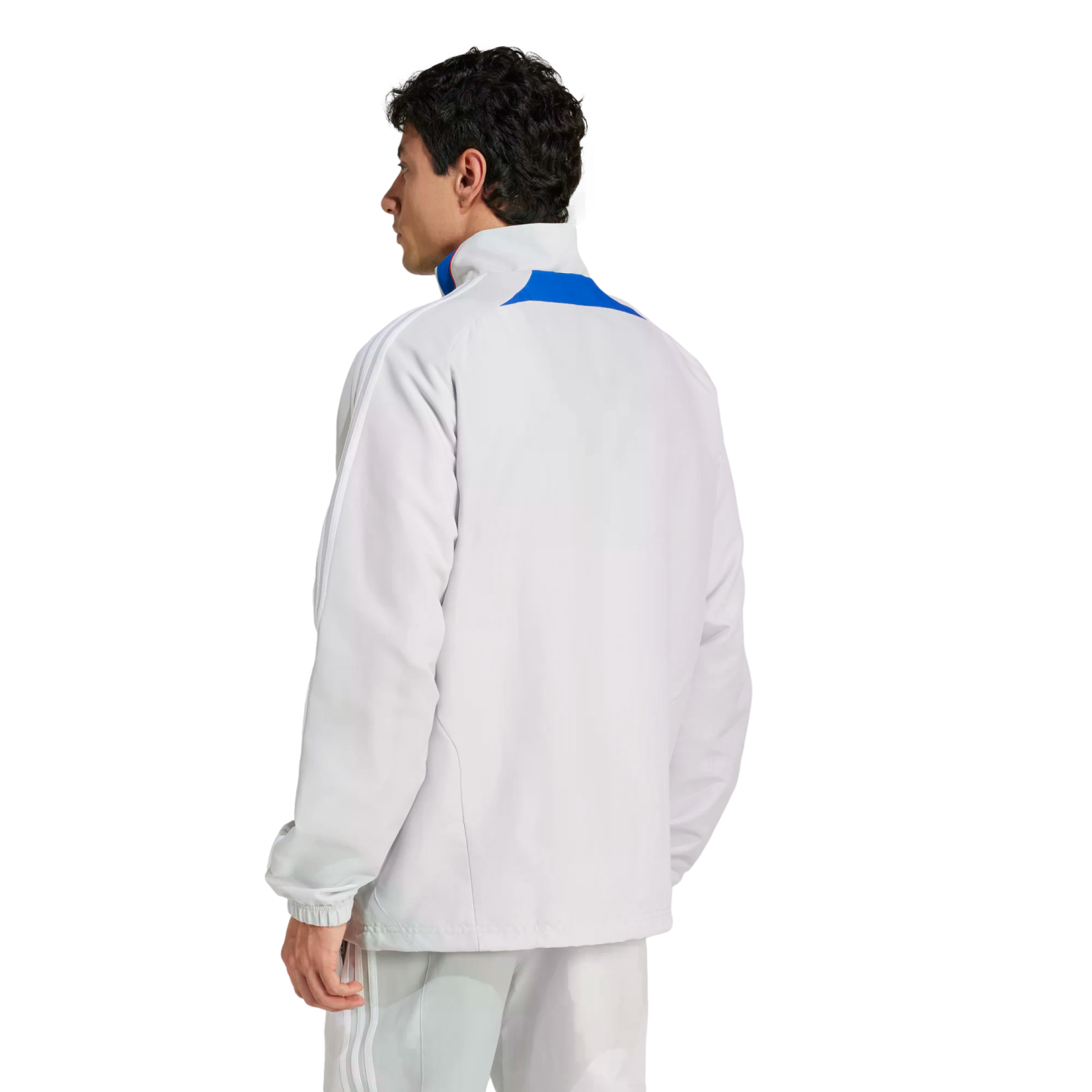 Rear view of a man wearing a light grey Adidas track jacket with blue accents and matching track pants against a plain white background.