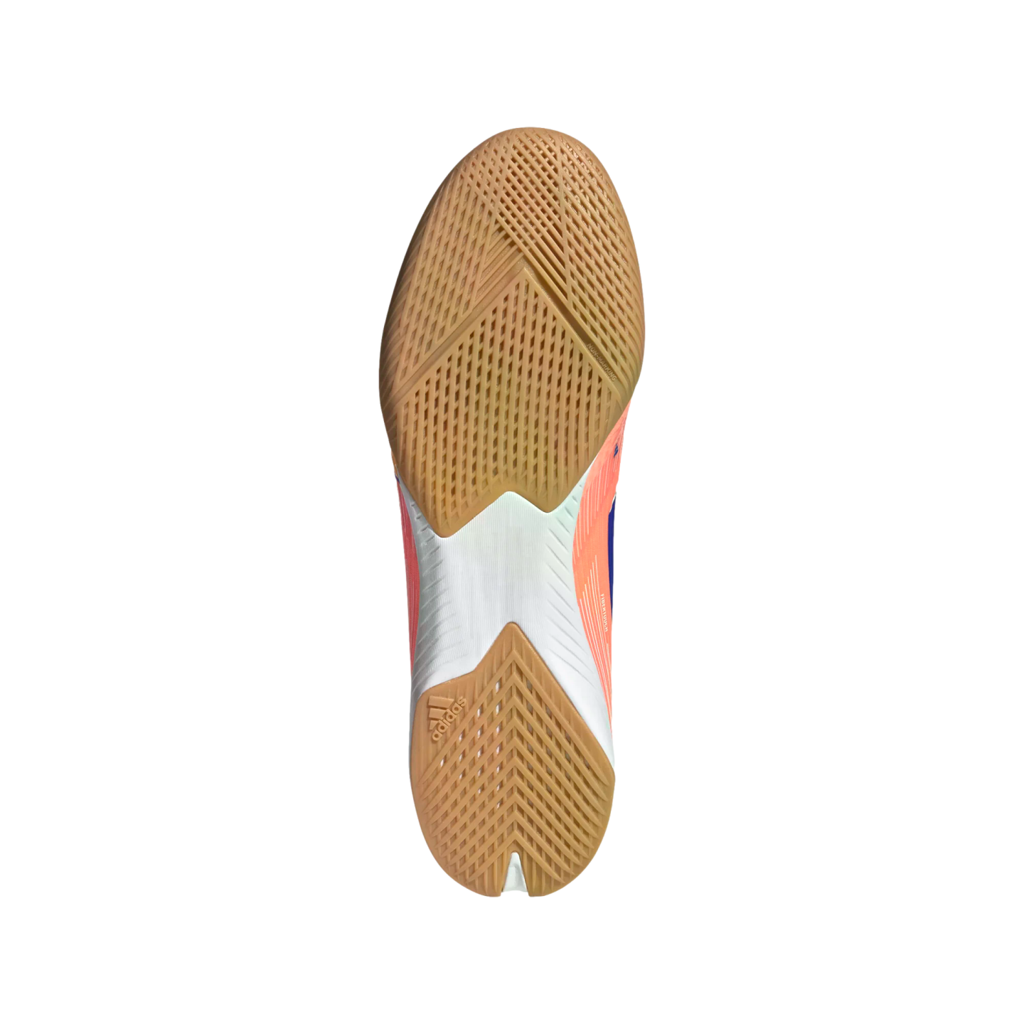 The underside of an Adidas indoor soccer shoe shows a gum rubber outsole with grid and chevron traction patterns, a white midfoot, and a small logo on the heel.