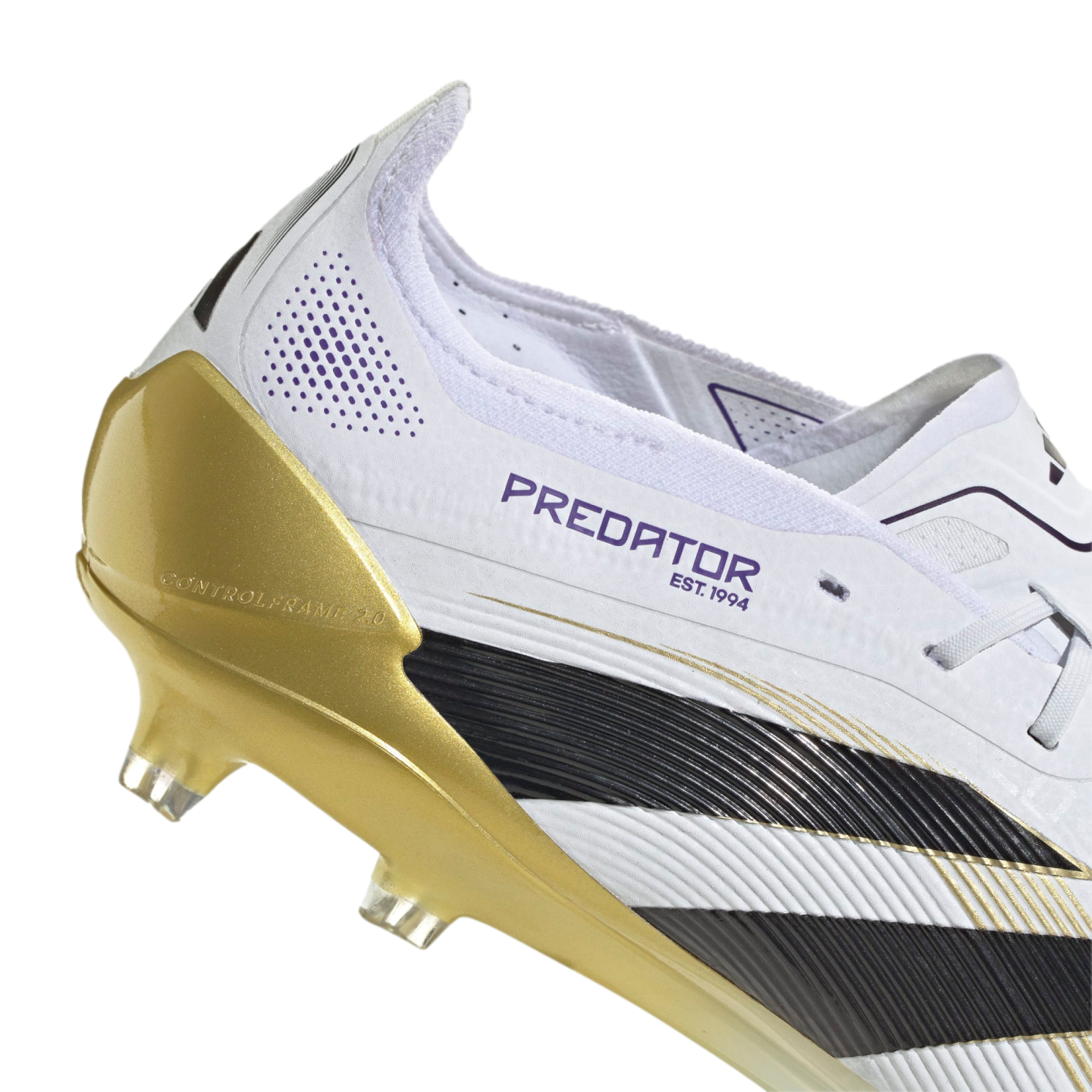 Close-up of a white Adidas Predator soccer cleat with black stripes, a metallic gold soleplate labeled "Controlframe 2.0," and purple "PREDATOR EST. 1994" branding.