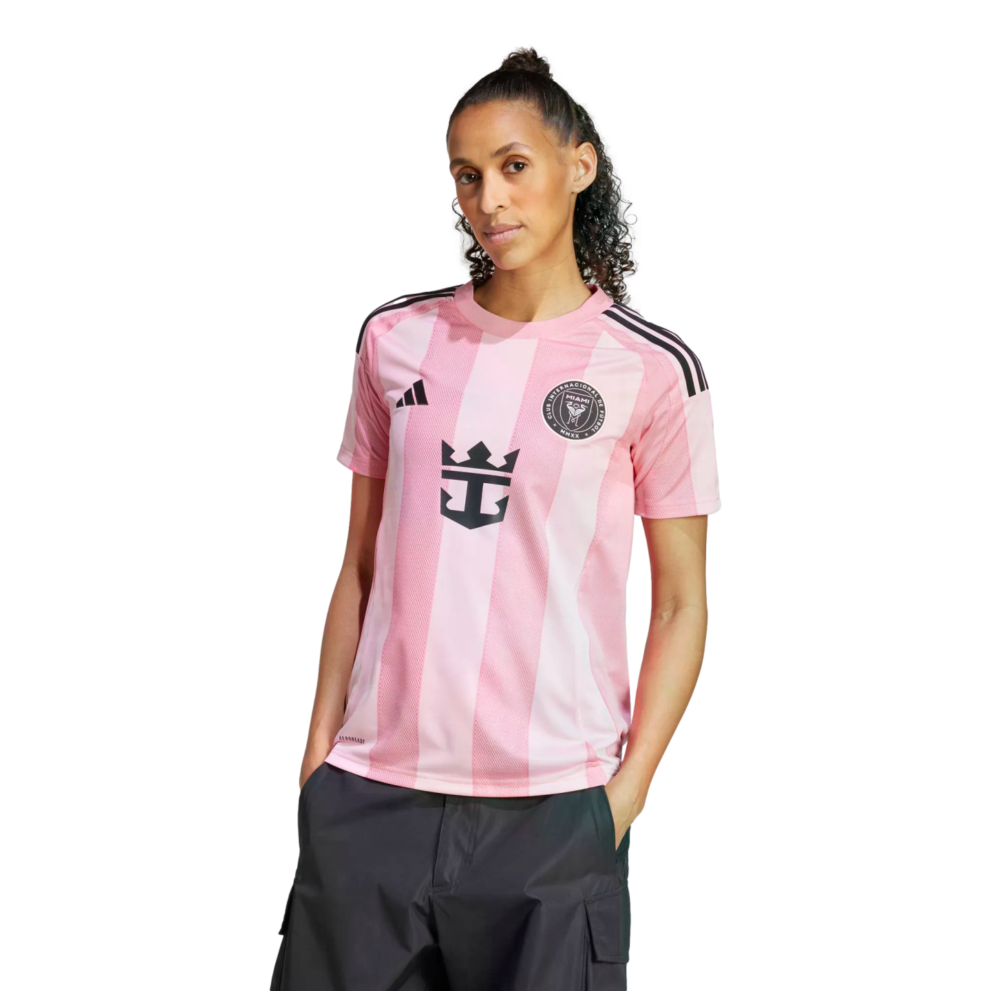 Woman wearing a pink striped Inter Miami CF soccer jersey and dark cargo pants against a white background.