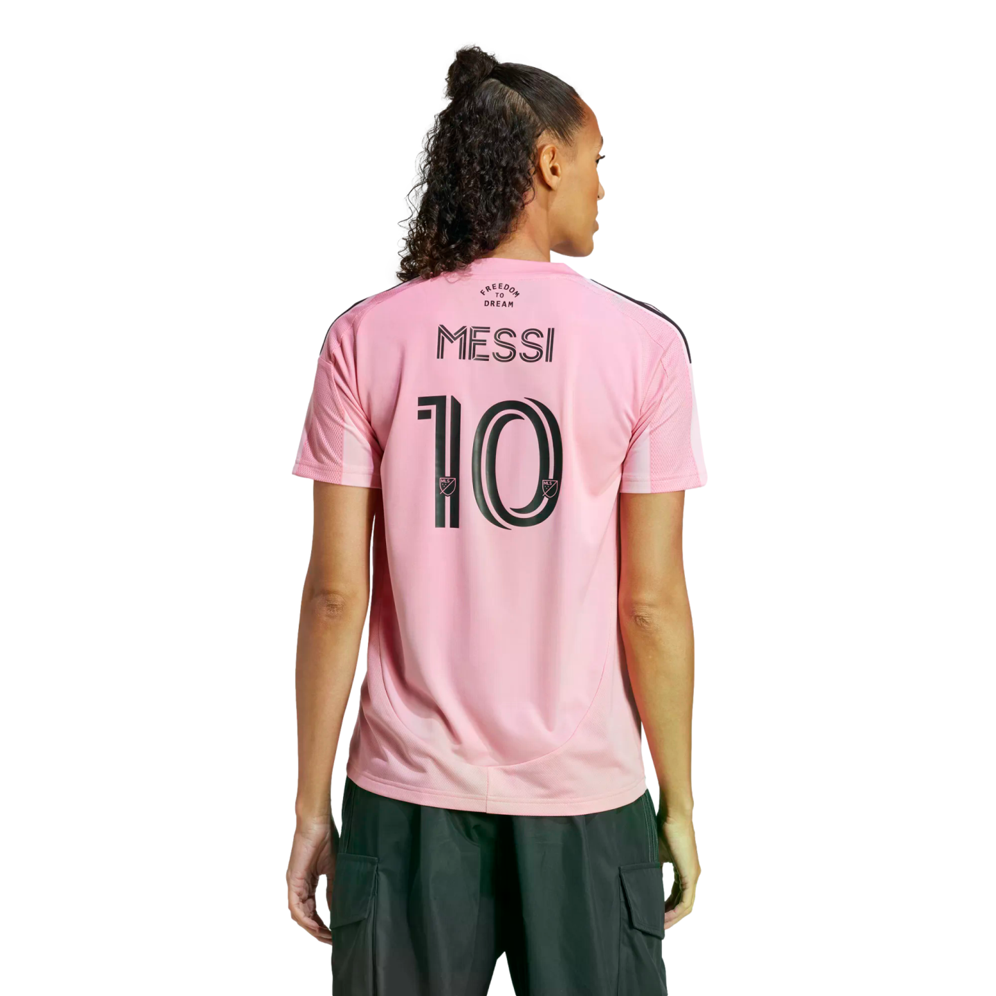 Rear view of a person wearing a pink Inter Miami soccer jersey with "MESSI 10" on the back and dark cargo pants against a white background.