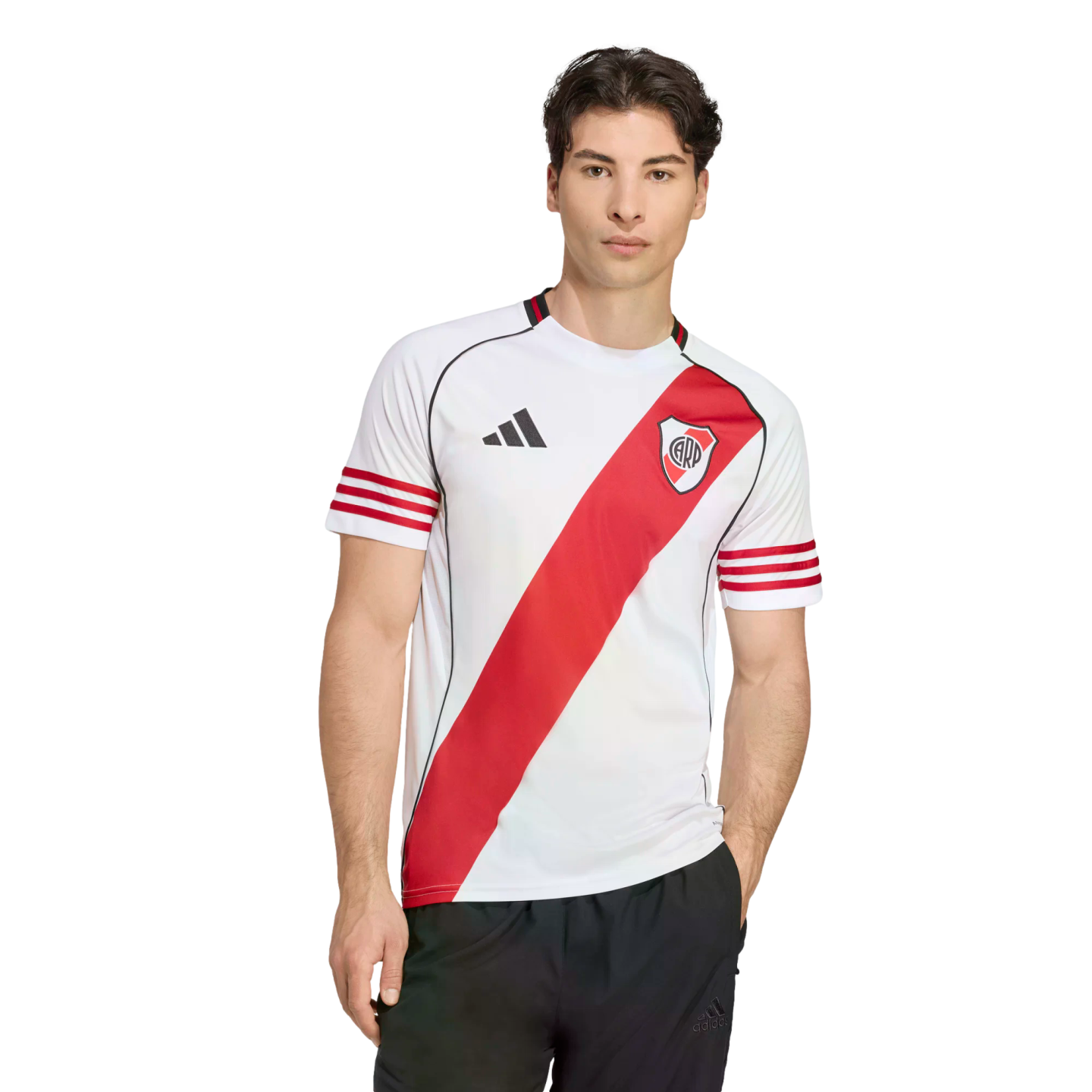 A man wearing a white River Plate football jersey with a red diagonal sash and black shorts against a plain white background.