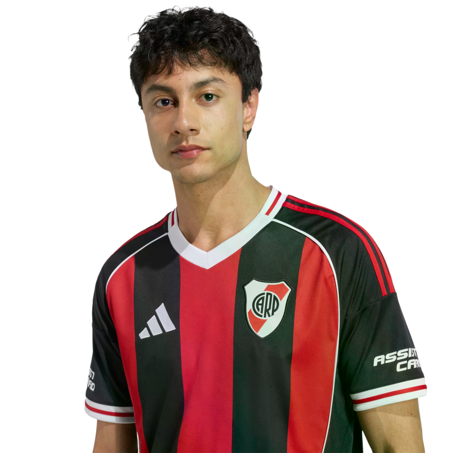 Portrait of a young man with dark wavy hair wearing a red and black striped River Plate soccer jersey against a plain white background.