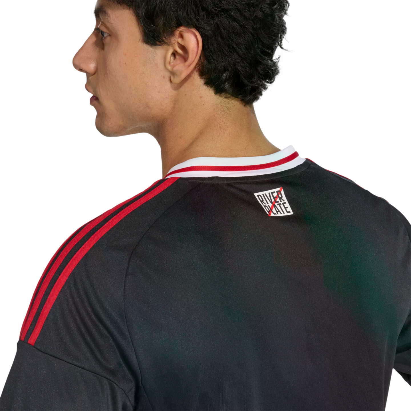 Profile and back view of a man wearing a black sports jersey with red stripes on the shoulders and a small "River Plate" logo on the upper back.