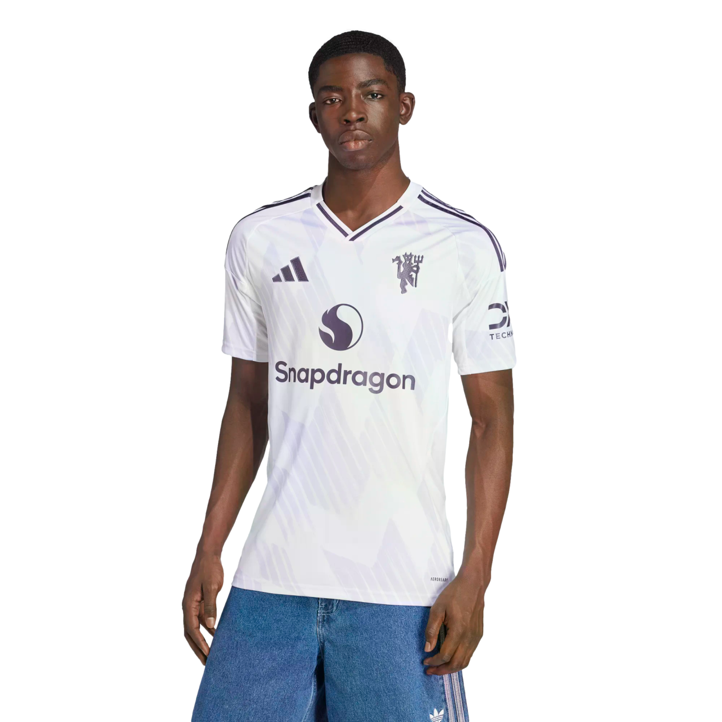 A man modeling a white Manchester United soccer jersey with a Snapdragon logo, posed against a black background.