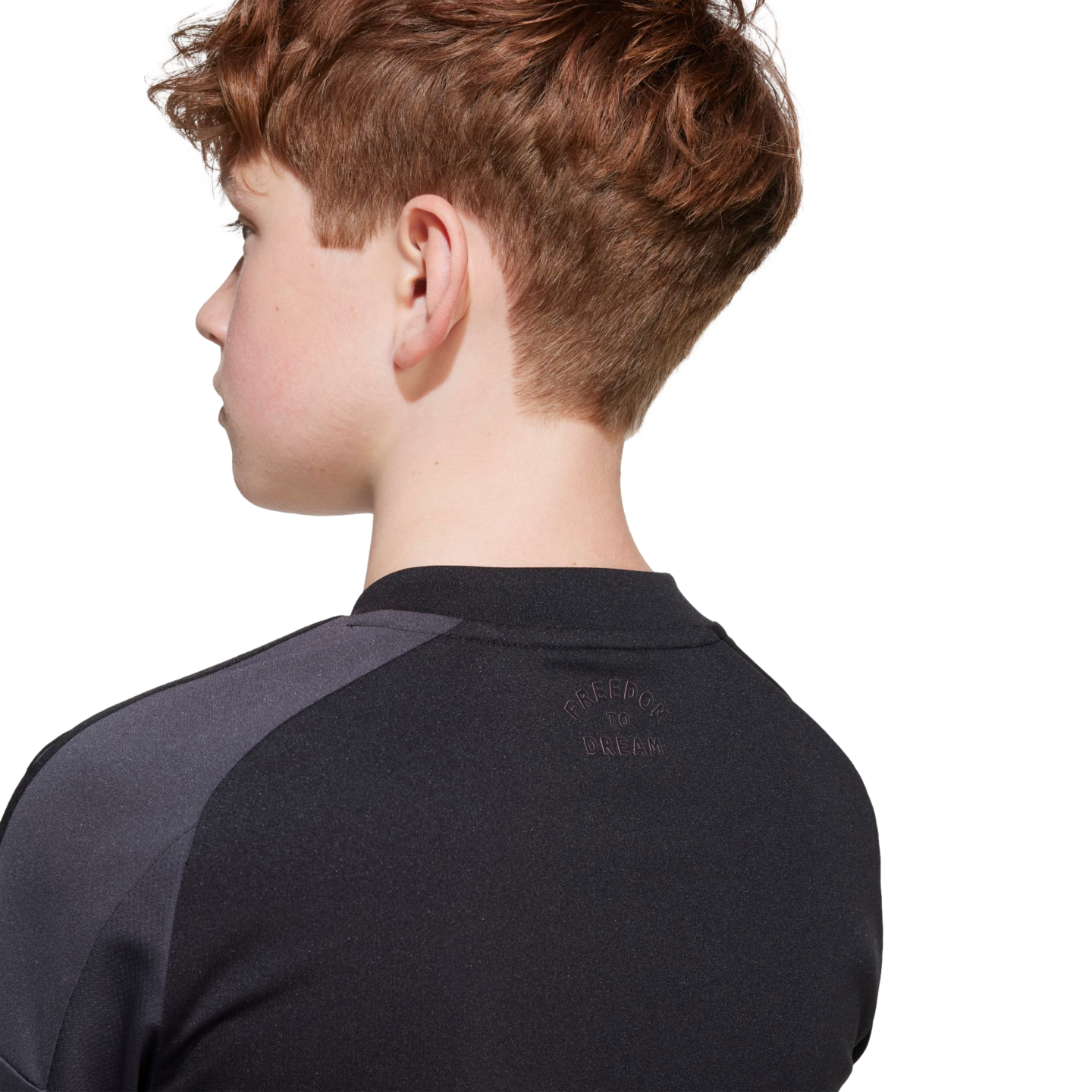 Side and back view of a youth with reddish-brown hair wearing a black athletic jersey with "FREEDOM TO DREAM" embossed on the back neck.