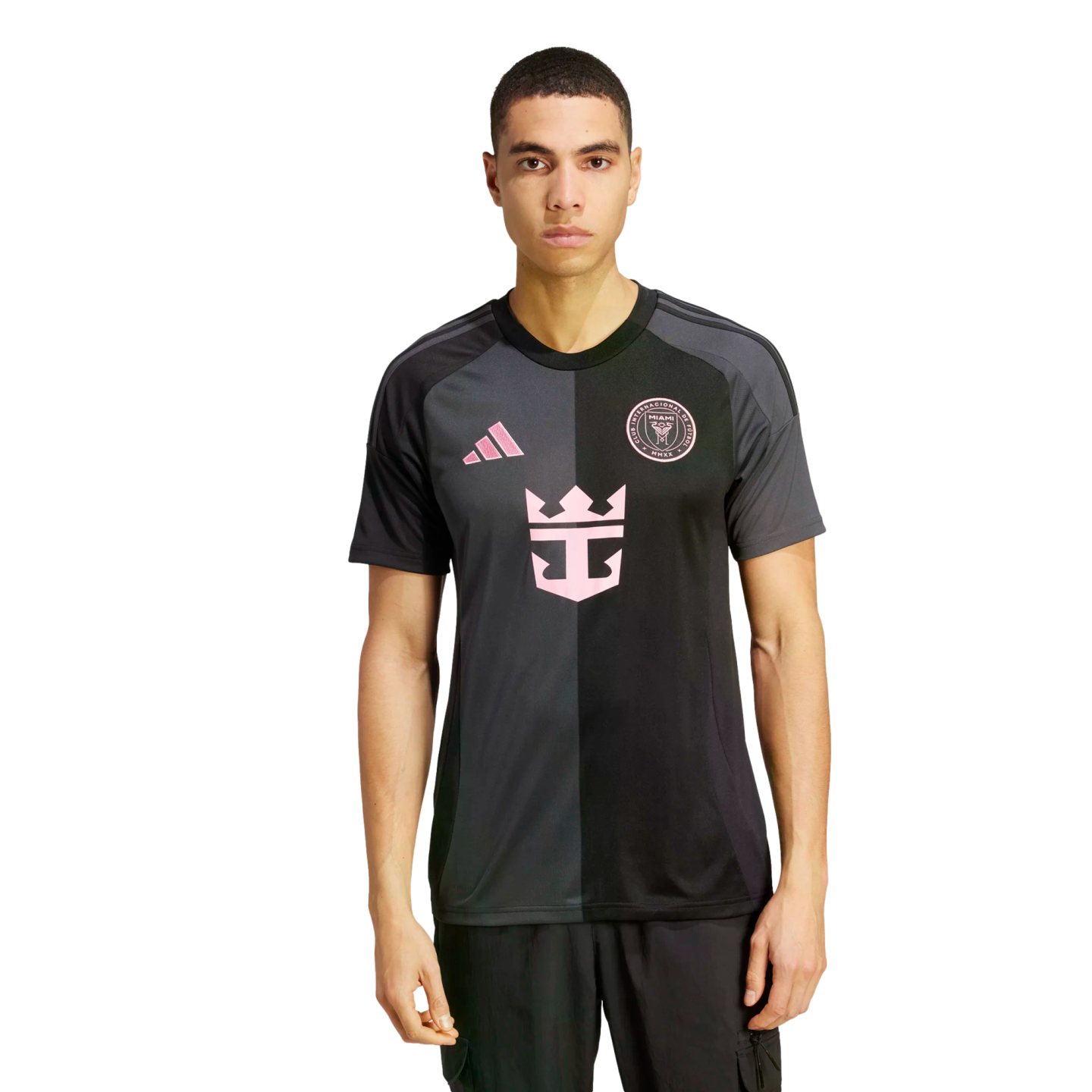 A man models a two-toned grey and black Inter Miami CF soccer jersey featuring pink logos on a plain white background.
