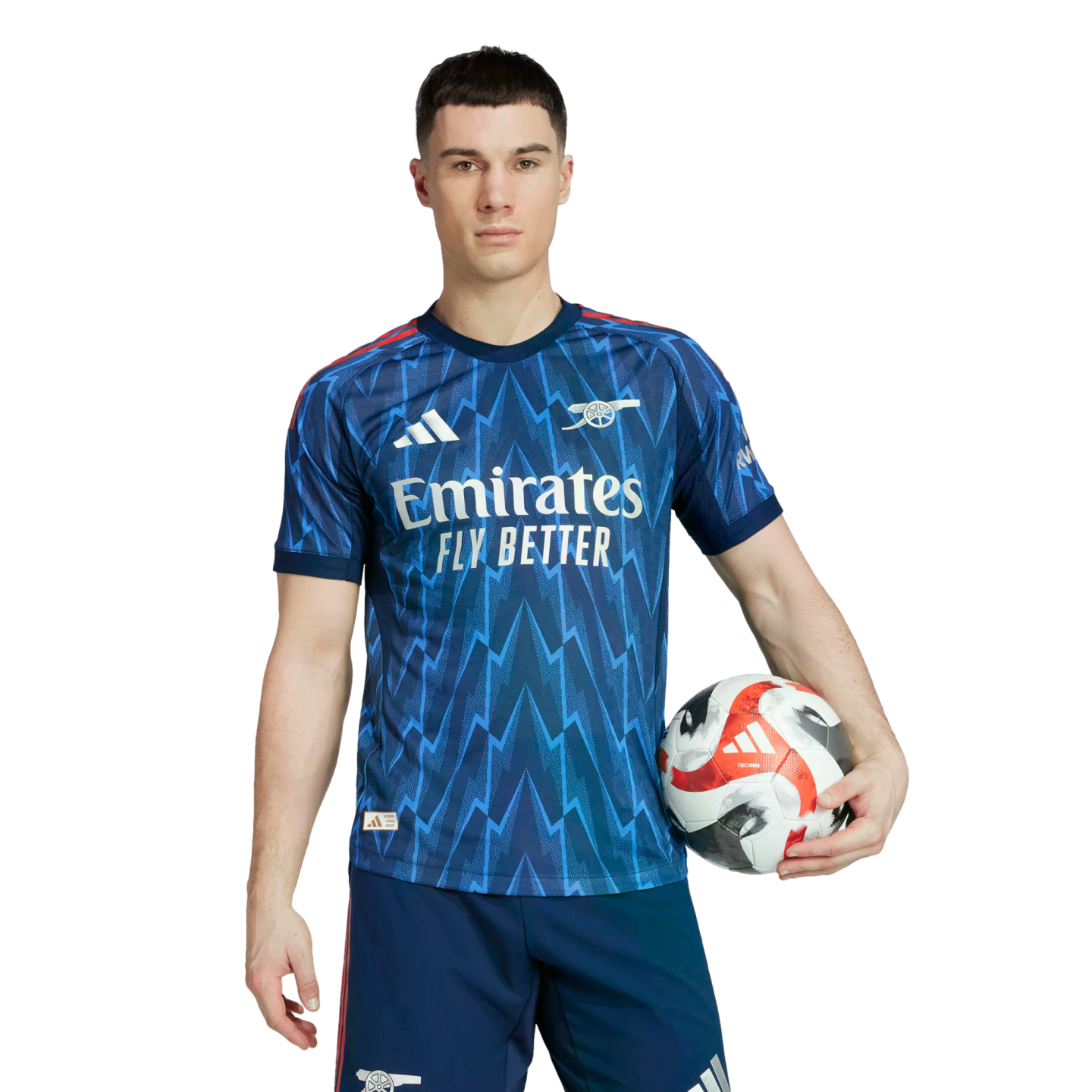 A man in a blue Arsenal soccer jersey with a lightning bolt pattern, holding a soccer ball against a black background.