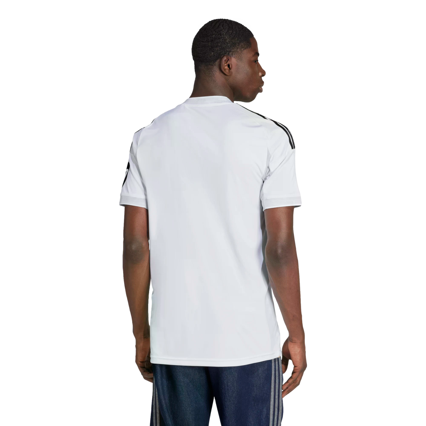 Rear view of a man wearing a white short-sleeved athletic jersey with black stripes on the shoulders and navy blue shorts.
