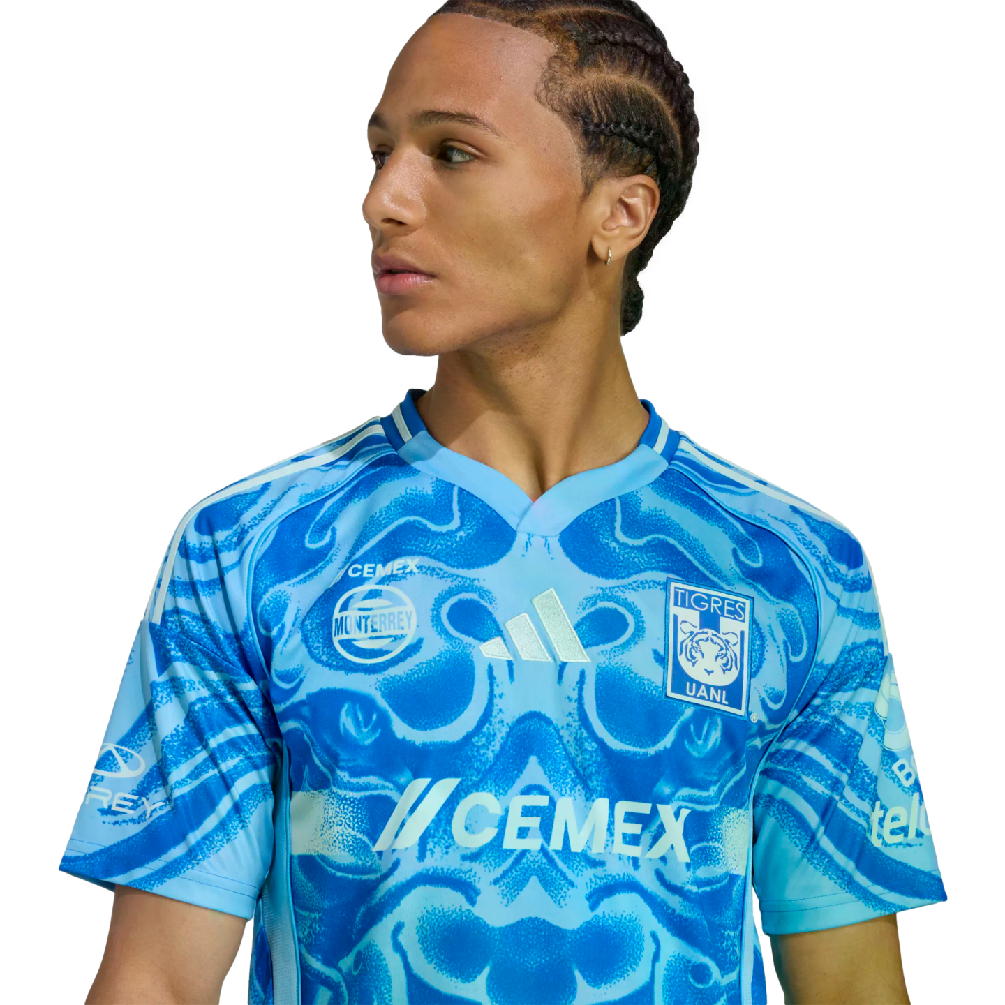 A young man in a blue marbled Tigres UANL soccer jersey looking to the side against a black background.