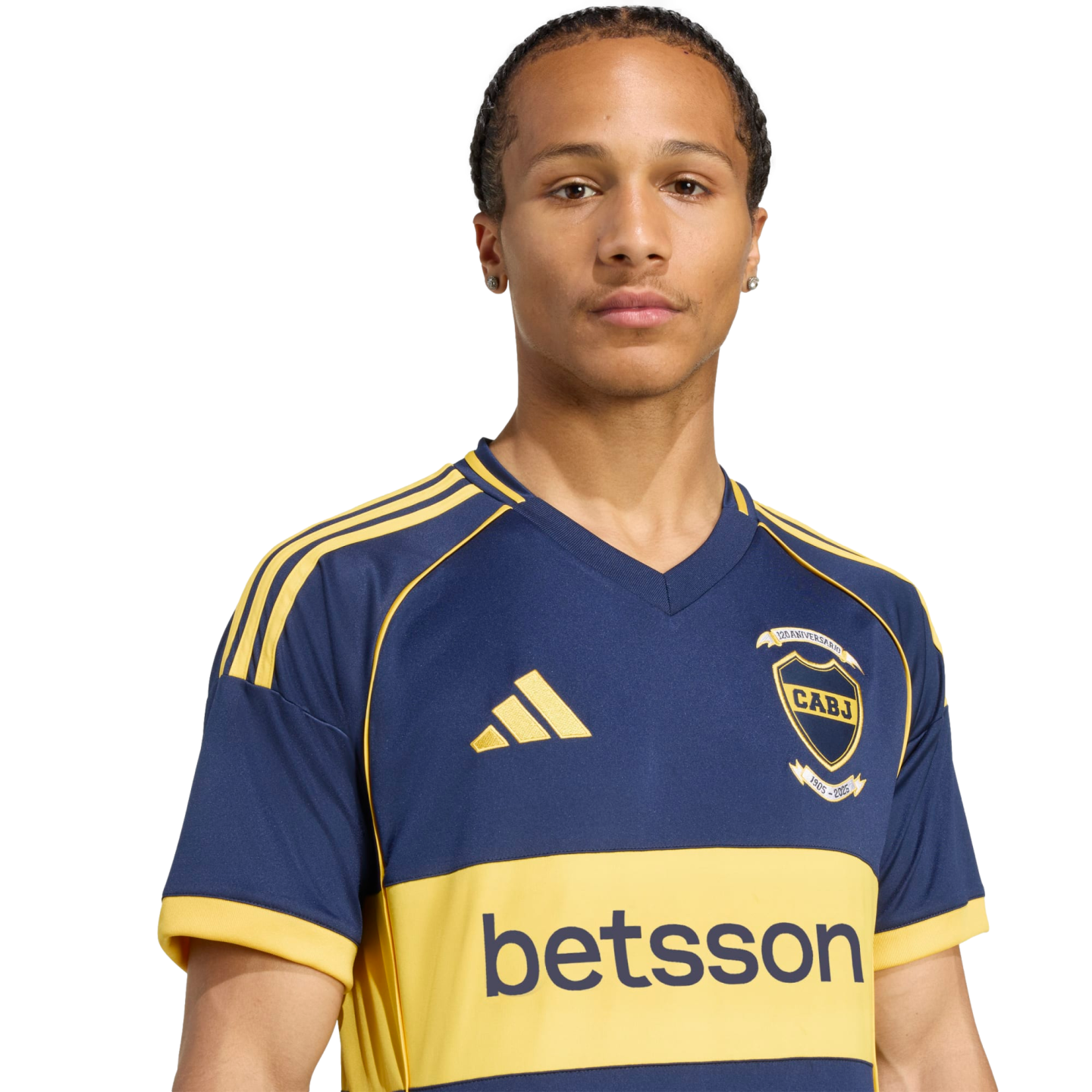 A young man with braided hair wears a blue and yellow Boca Juniors soccer jersey against a white background.