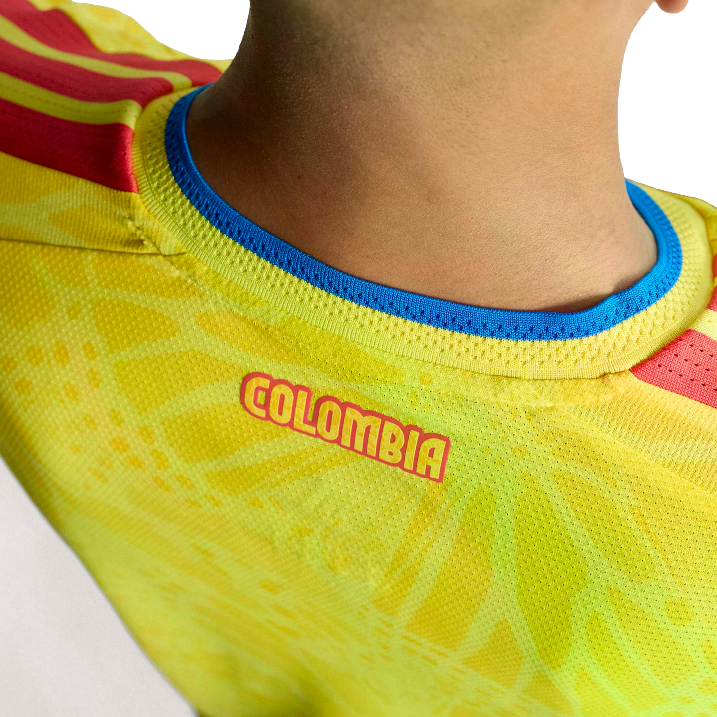 Close-up of the back neckline of a yellow Colombia soccer jersey, featuring red "COLOMBIA" lettering and a blue-trimmed collar.