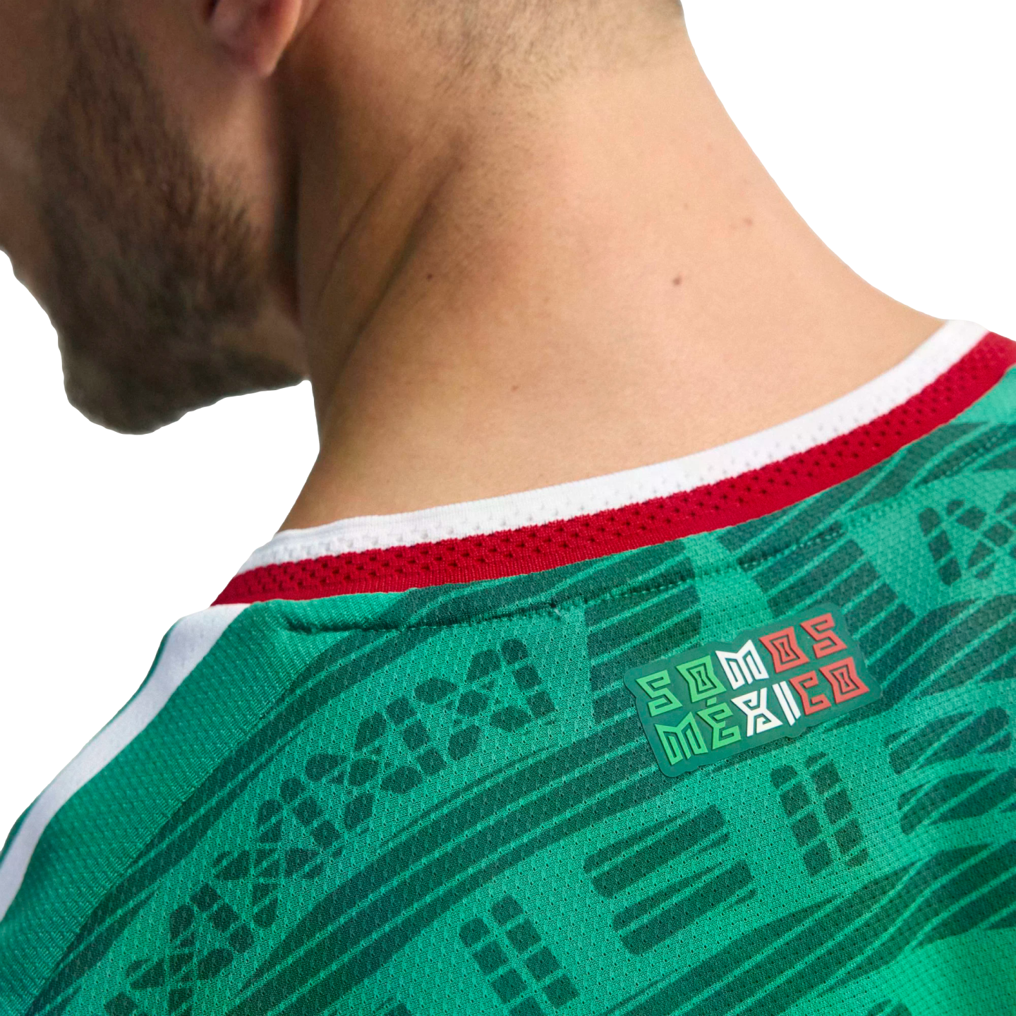 Close-up of the back of a green Mexico soccer jersey featuring a "SOMOS MÉXICO" badge below a red and white collar.