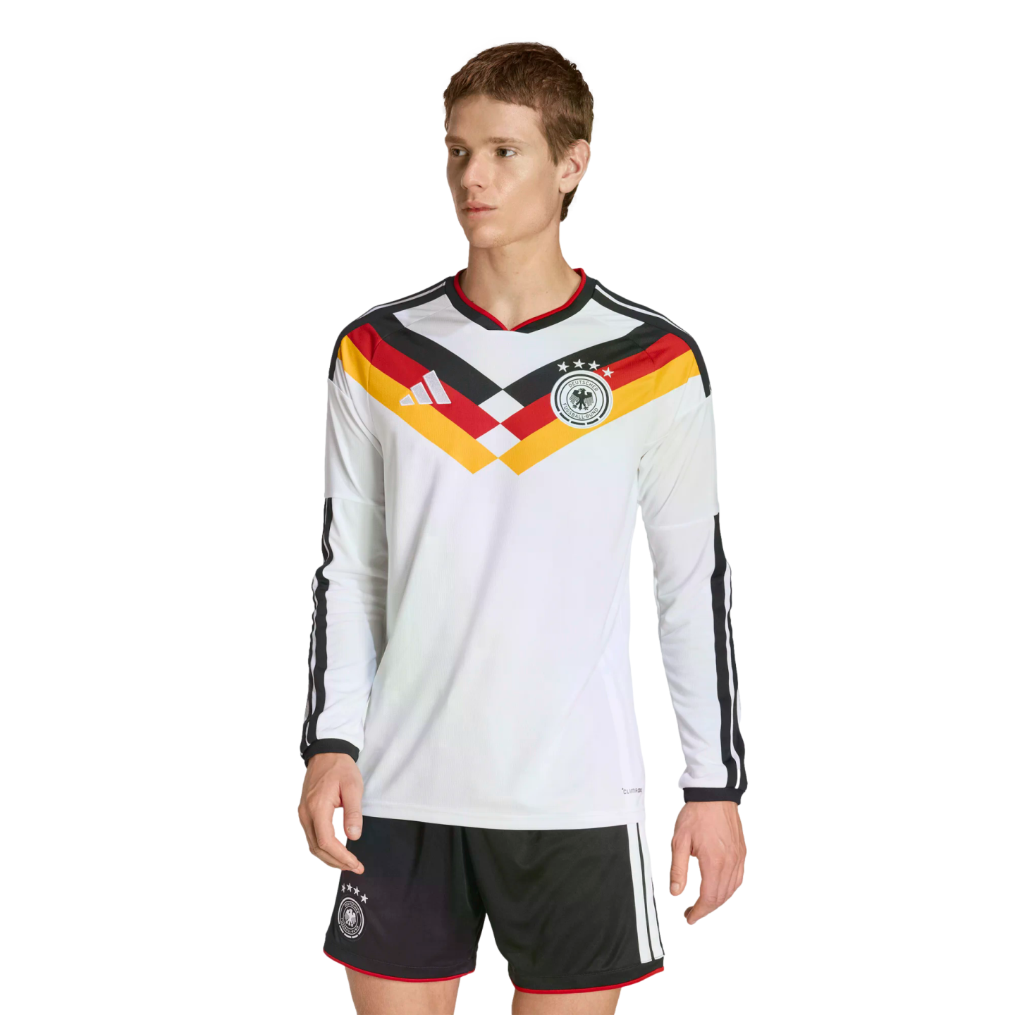 A man modeling a white long-sleeved Germany soccer jersey with a black, red, and yellow chevron design and matching black shorts against a solid black background.