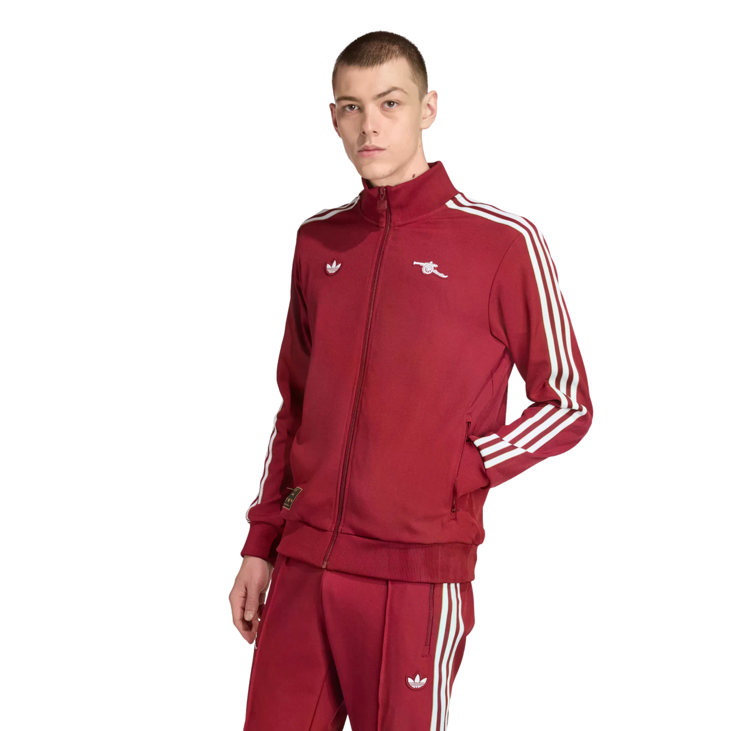 A young man models a maroon Adidas tracksuit with white stripes and an Arsenal FC cannon logo against a black background.