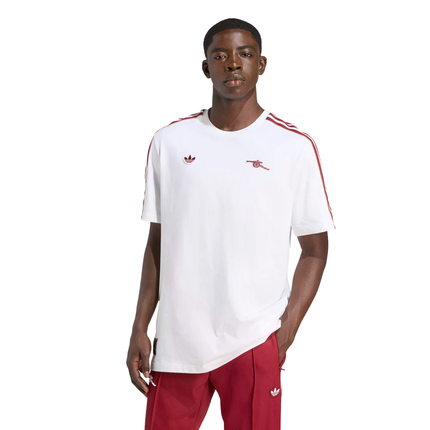 A man models a white Adidas Arsenal T-shirt with red accents and matching red track pants against a plain black background.