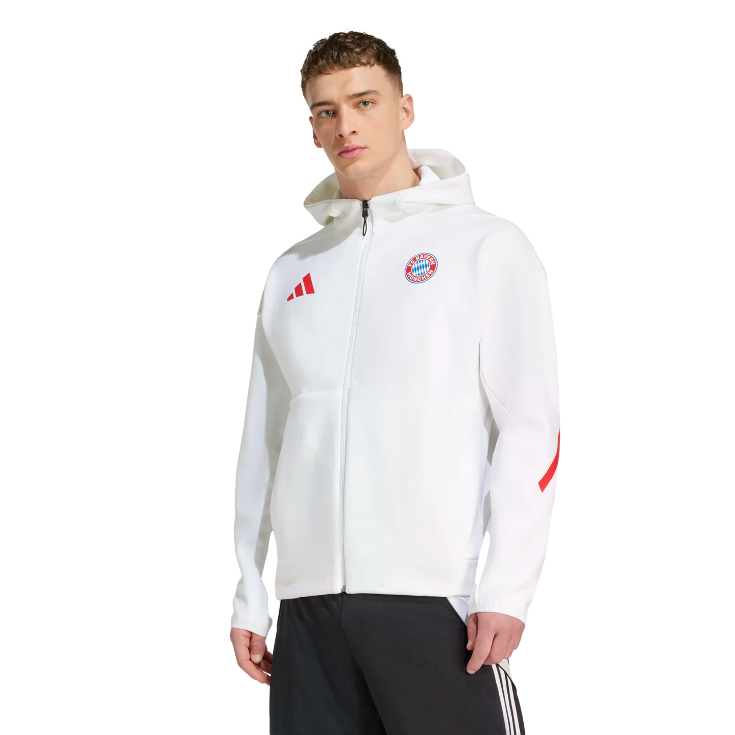 A man wearing a white FC Bayern Munich zip-up hoodie with a red Adidas logo and black track pants.