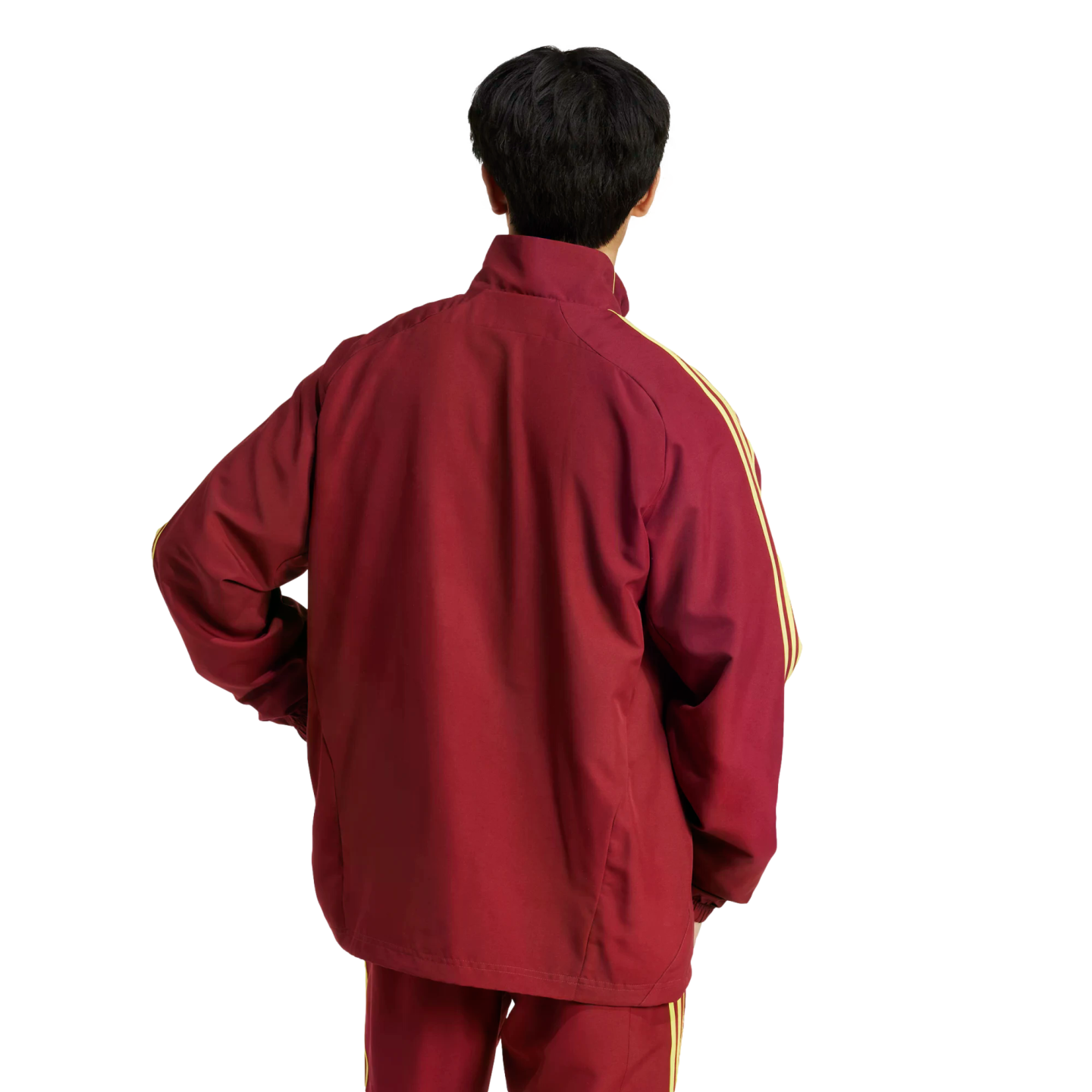 Rear view of a person with short black hair wearing a maroon tracksuit with yellow stripes on the sleeves against a white background.