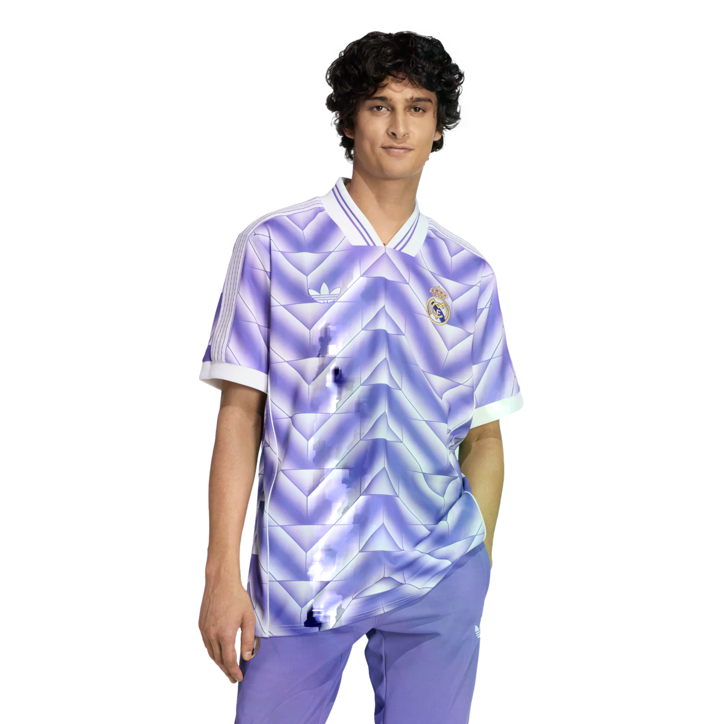 A young man with dark curly hair wearing a purple and white geometric Real Madrid jersey and matching pants against a solid black background.