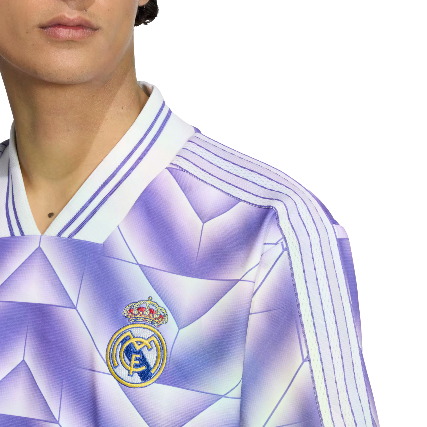 Close-up of a person wearing a purple Real Madrid soccer jersey with a geometric pattern, white stripes on the shoulders, and the team crest on the chest.