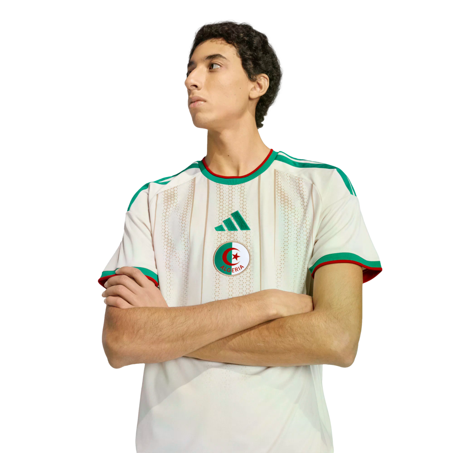 A man with crossed arms wearing an Algeria national team soccer jersey against a black background.