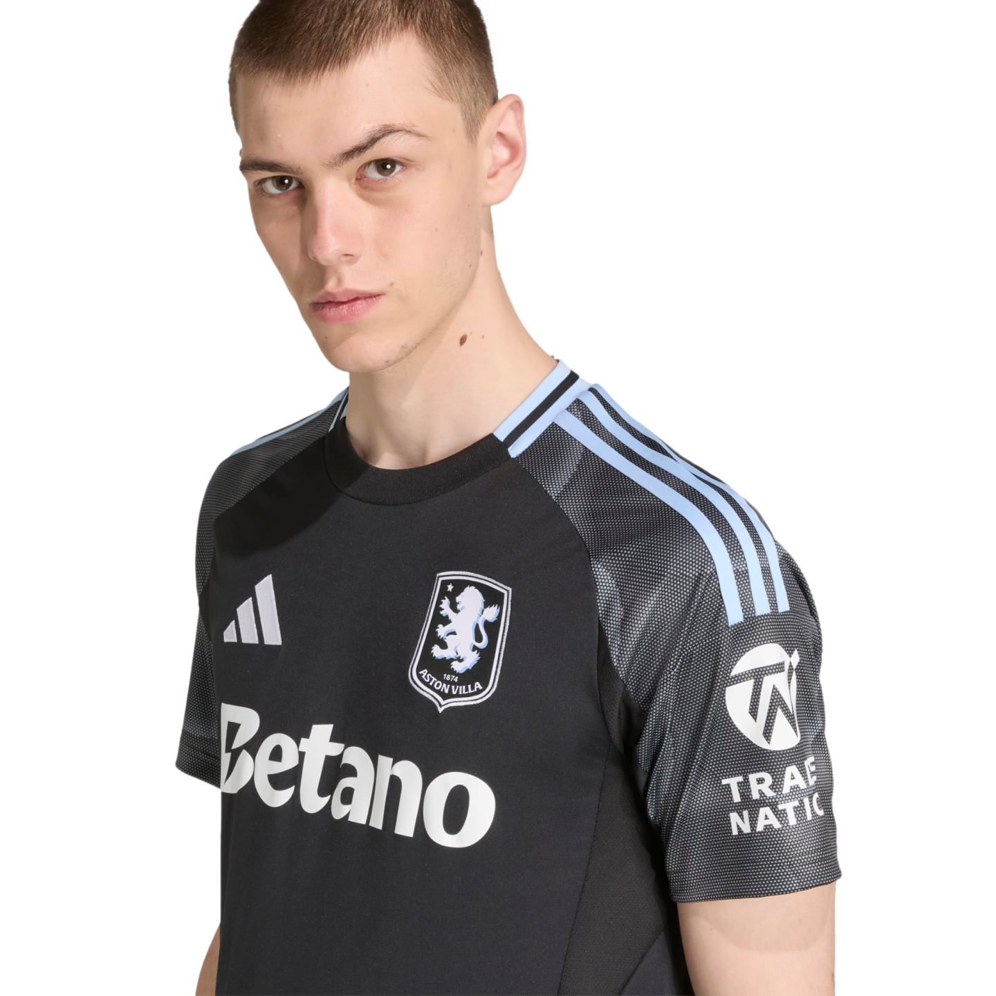 Young man wearing a black Aston Villa soccer jersey with light blue shoulder stripes and sponsor logos, posing against a plain black background.