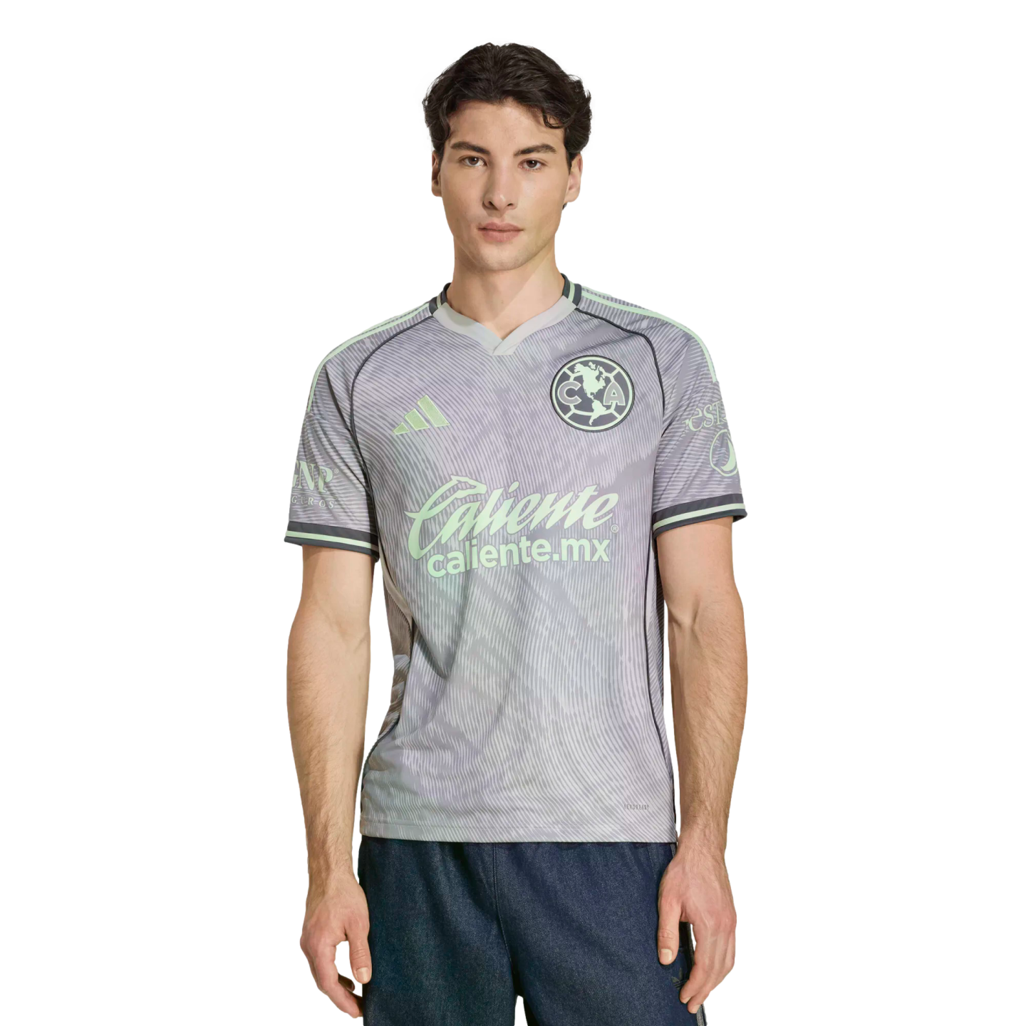 Man modeling a grey and mint green Club América soccer jersey with Adidas and Caliente.mx logos against a black background.