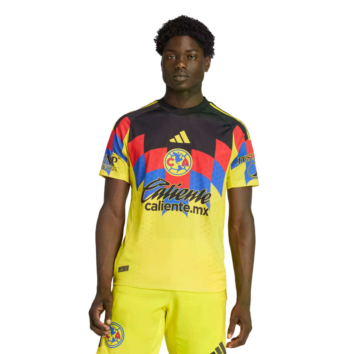 A man wearing a yellow Club América soccer kit with red and blue geometric patterns on the chest and sponsor logos, set against a black background.