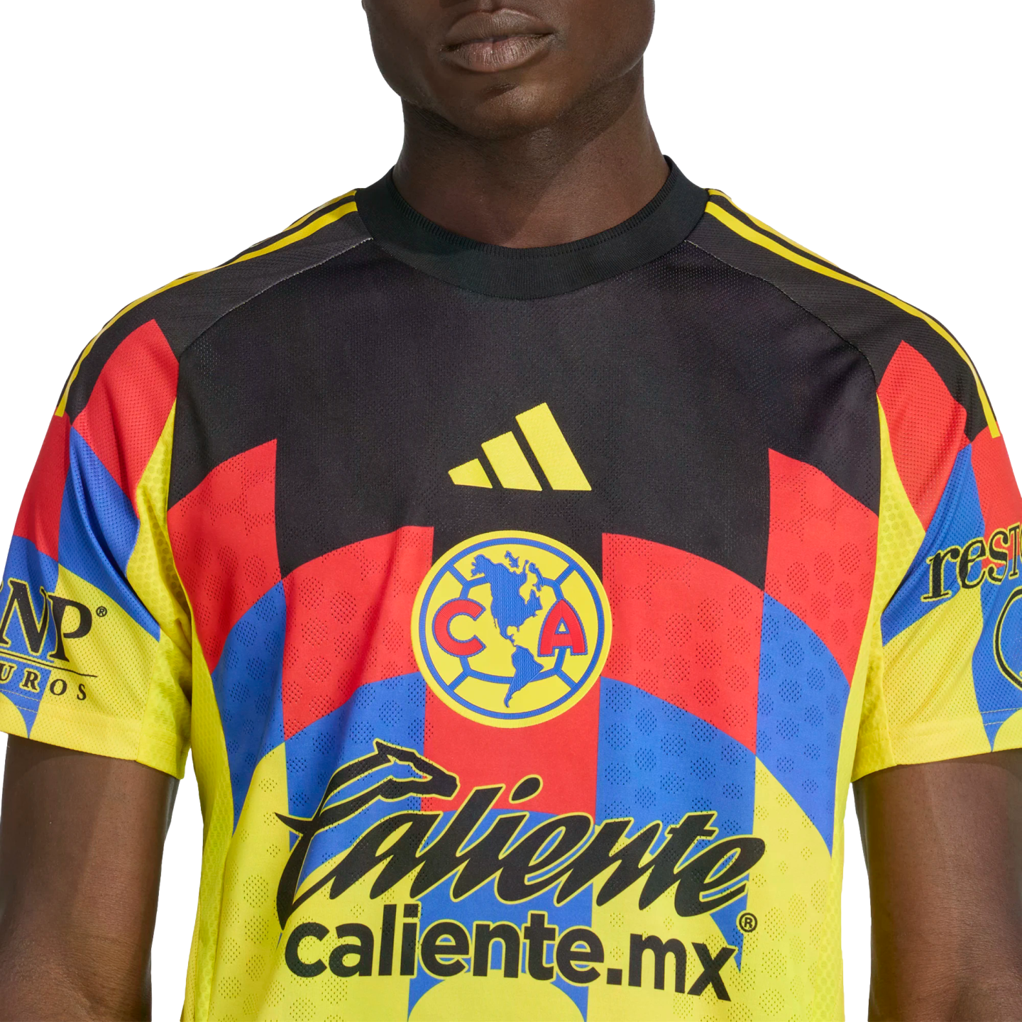 A person wearing a Club América soccer jersey with a black, yellow, red, and blue geometric pattern, featuring the team crest and various sponsor logos.