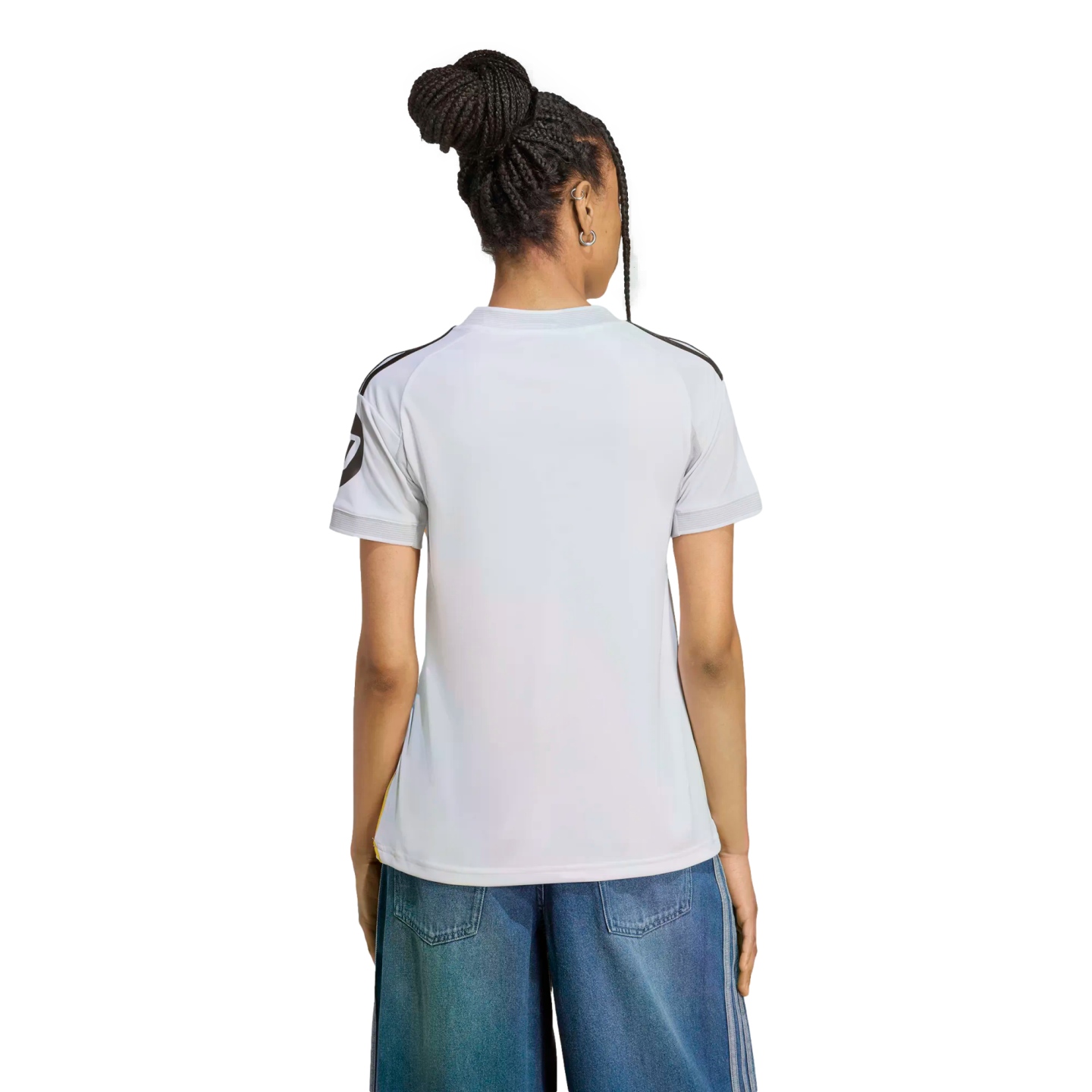 Back view of a person with braided hair in a bun, wearing a white t-shirt with black shoulder stripes and blue denim pants against a white background.