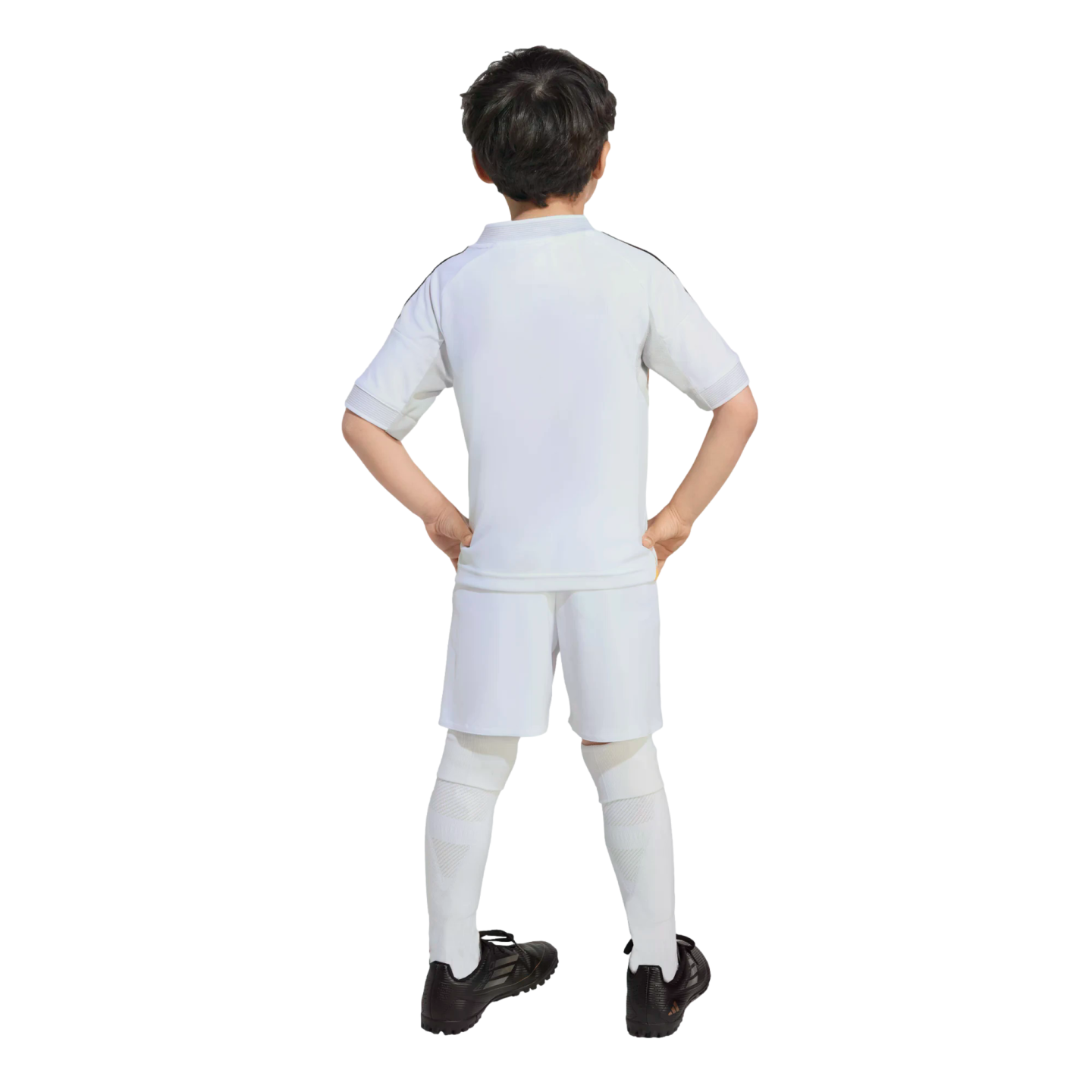 Rear view of a boy in a white soccer uniform with hands on his hips, wearing a white jersey, shorts, and tall socks with black cleats.