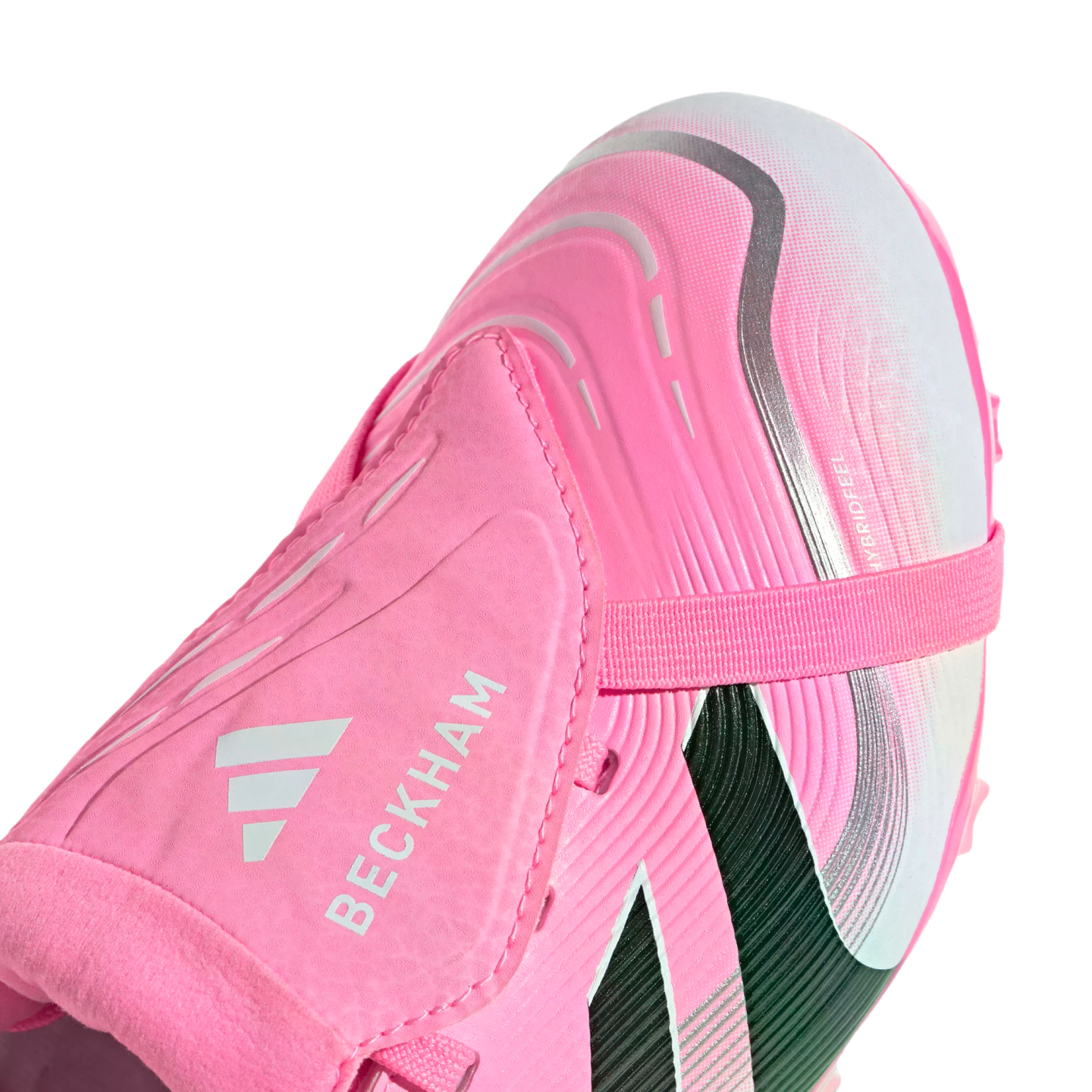 Close-up of a pink Adidas soccer cleat with "BECKHAM" and the Adidas logo printed on its fold-over tongue, set against a black background.