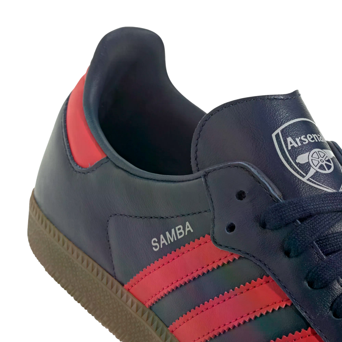 Close-up of a navy blue Adidas Samba sneaker featuring pink stripes and the Arsenal Football Club crest on the tongue.