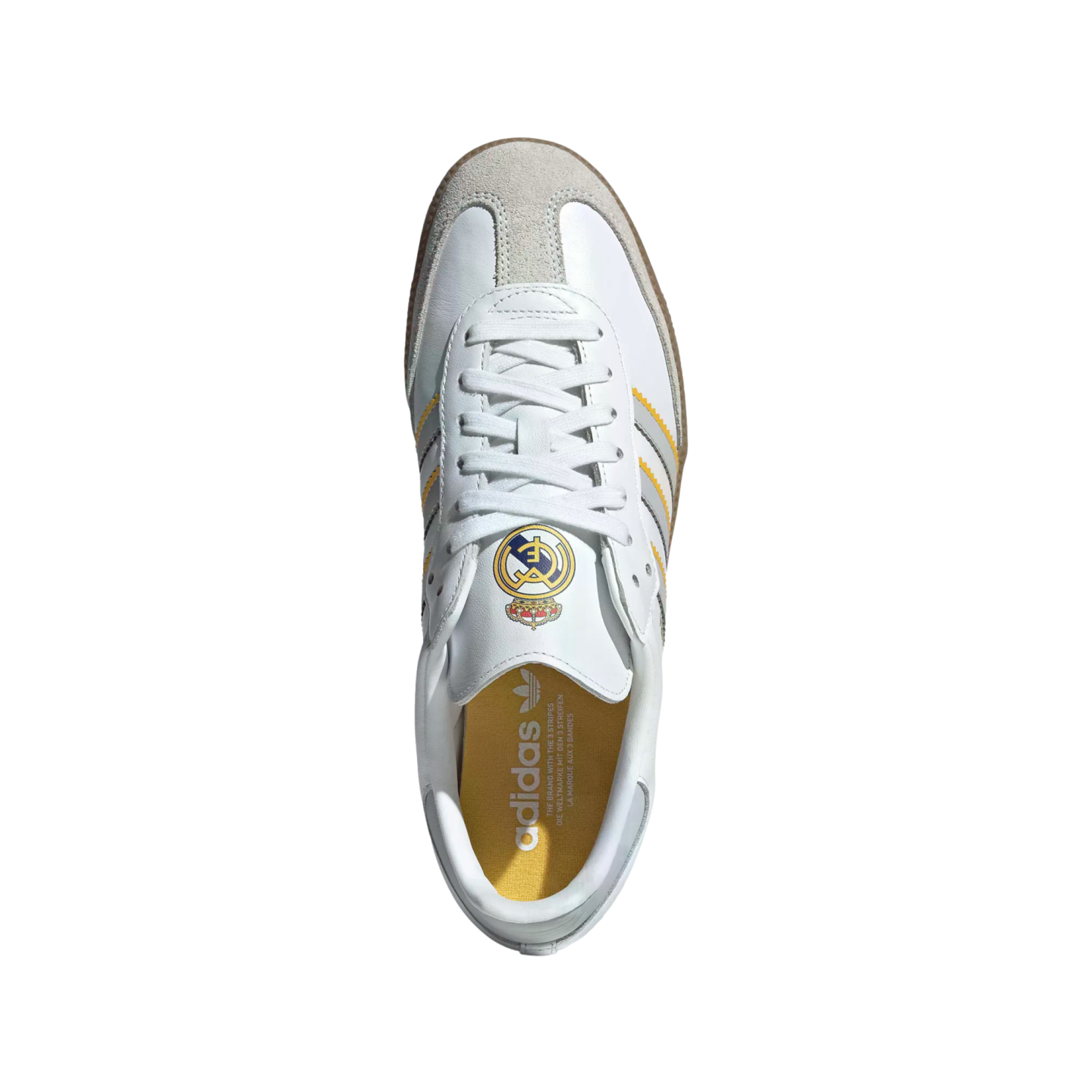 Top-down view of a white Adidas Samba sneaker featuring a Real Madrid crest on the tongue, grey and yellow side stripes, and a grey suede toe cap.