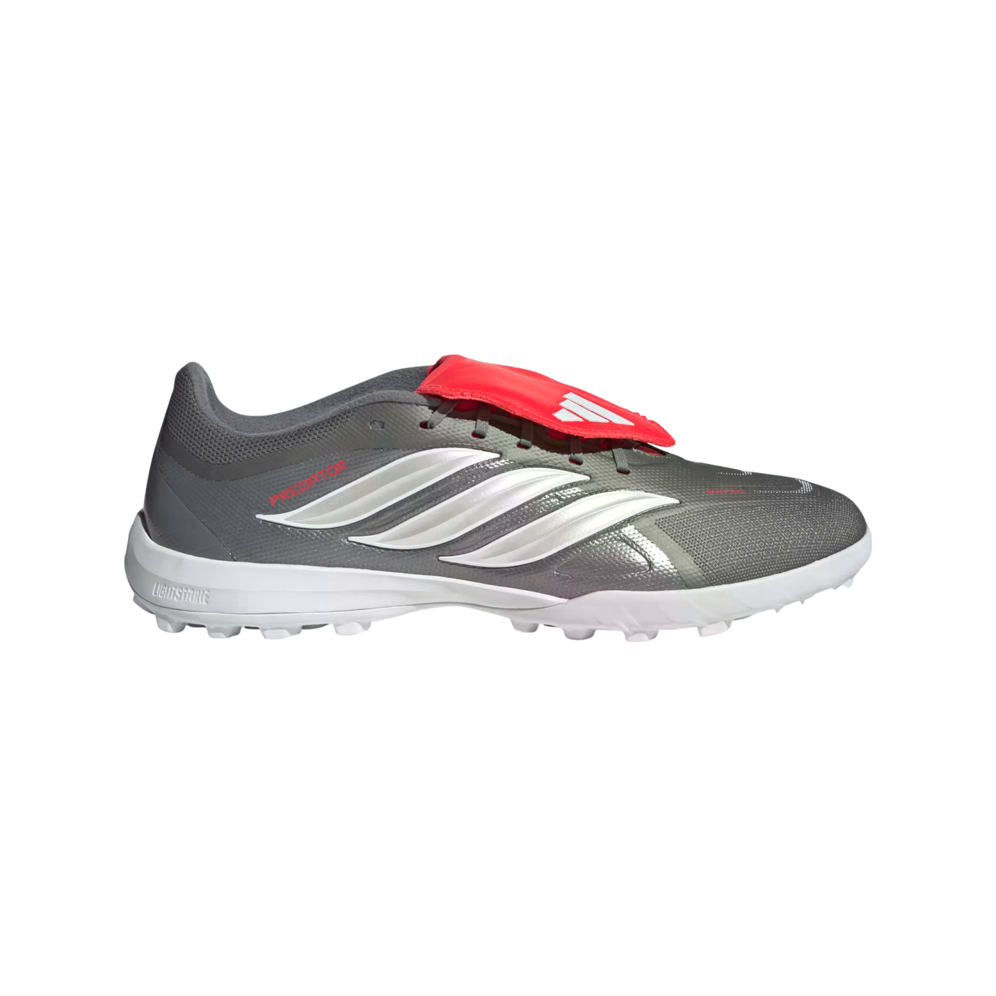 Profile view of a grey Adidas Predator soccer shoe featuring three white stripes, a red fold-over tongue with a white logo, and a white turf outsole.