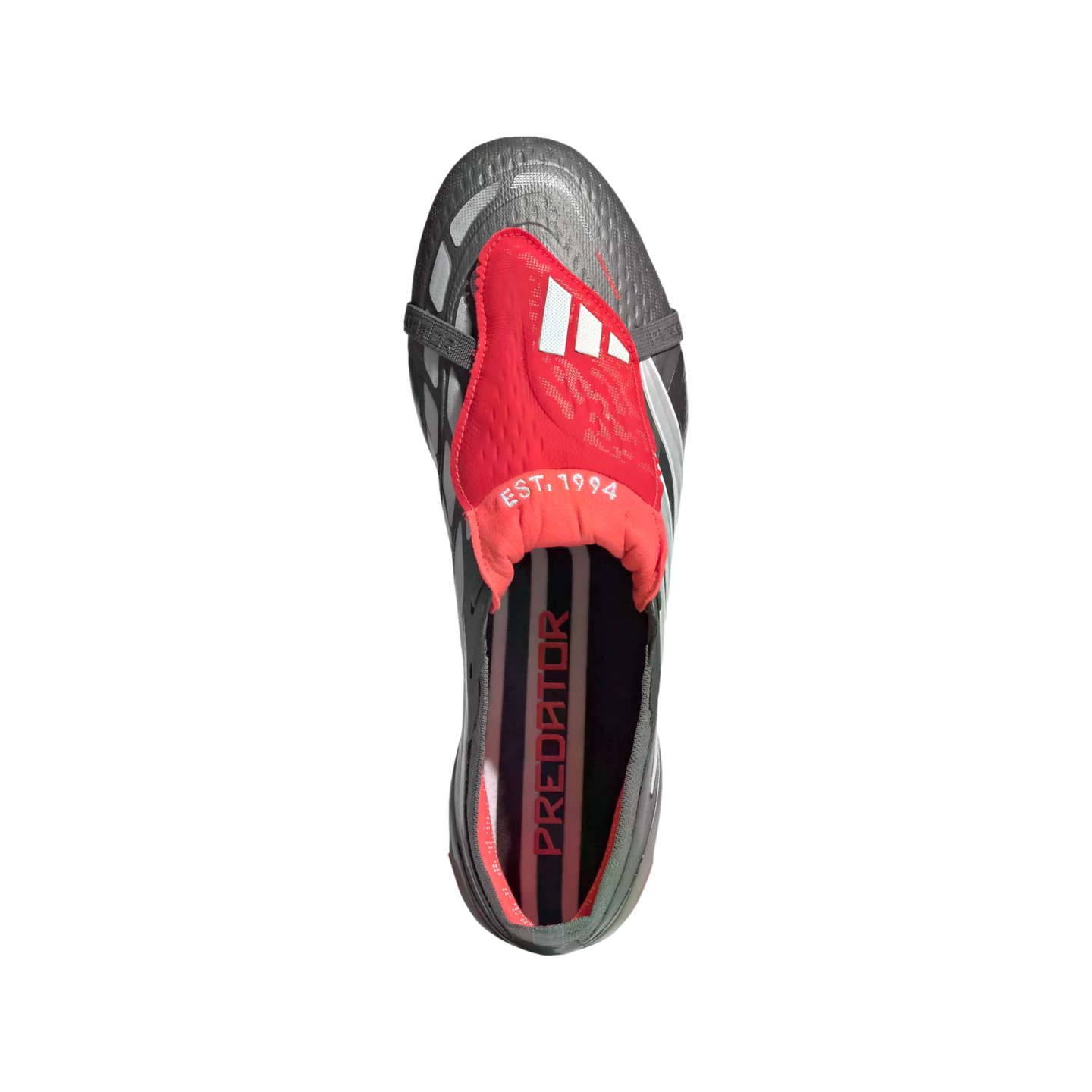 Top-down view of a grey and red Adidas Predator soccer cleat with a red fold-over tongue featuring "EST. 1994" and "PREDATOR" printed on the insole, set against a black background.